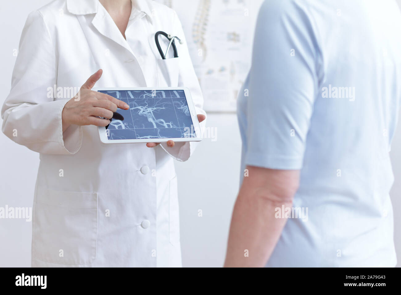 Stroke prevention concept: doctor with tablet pc showing her patient an mra image of her cerebral blood vessels. Stock Photo