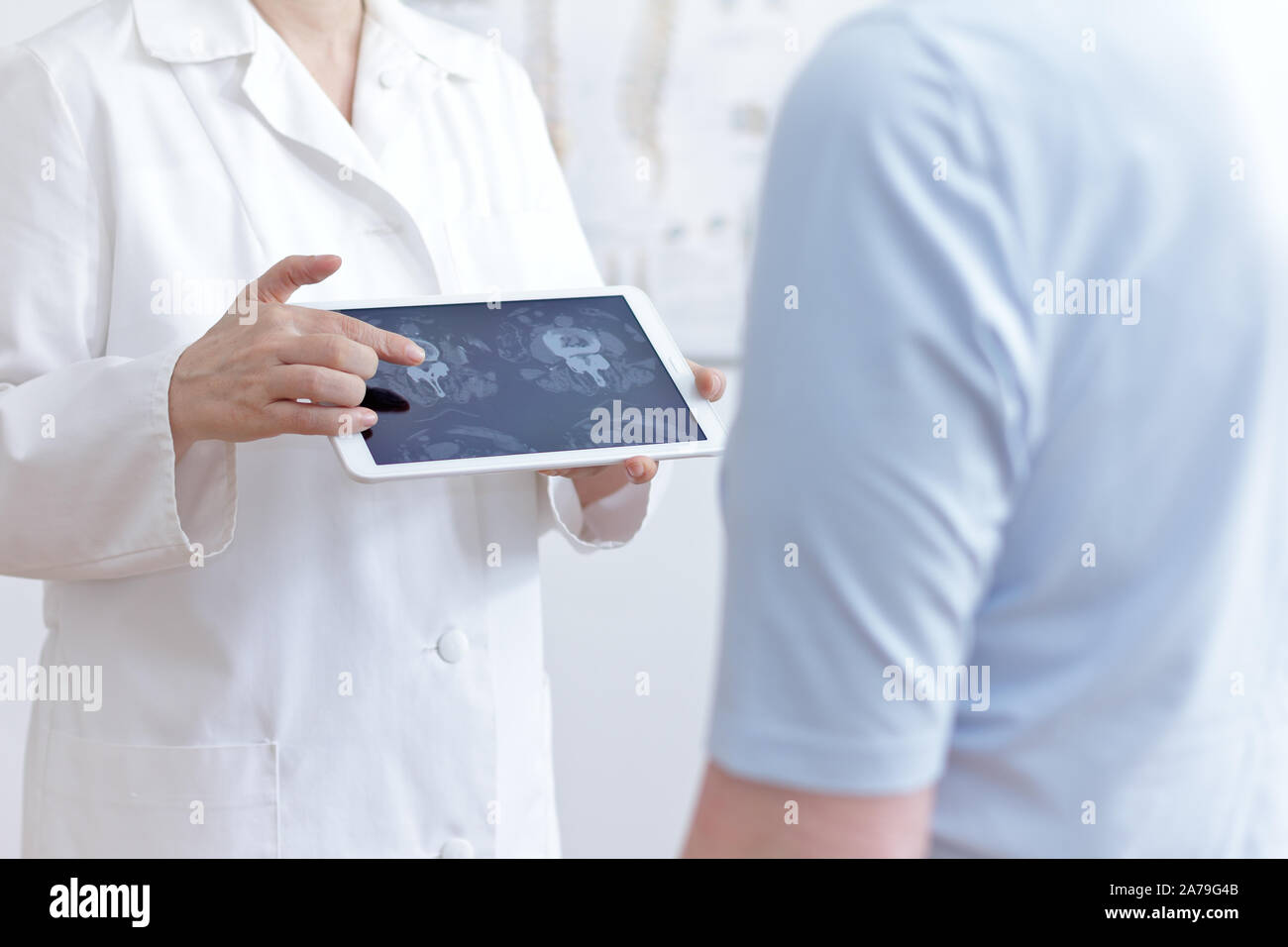 Back pain concept: doctor with tablet pc showing her patient cat scan images of her lumbar spines. Stock Photo