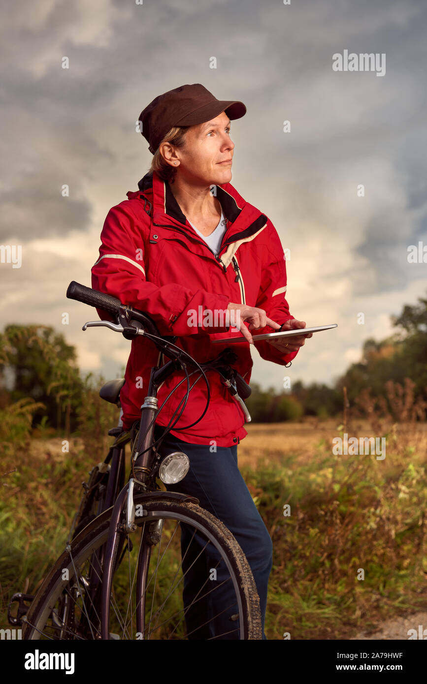 Middle age female cyclist checks weather forecast on a tablet pc Stock Photo