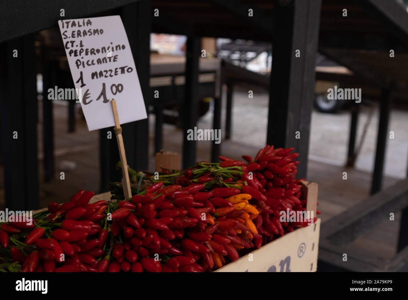 Bright red, hot and spicy, raw chillies displayed in bunches on a market stall in Venice. Stock Photo
