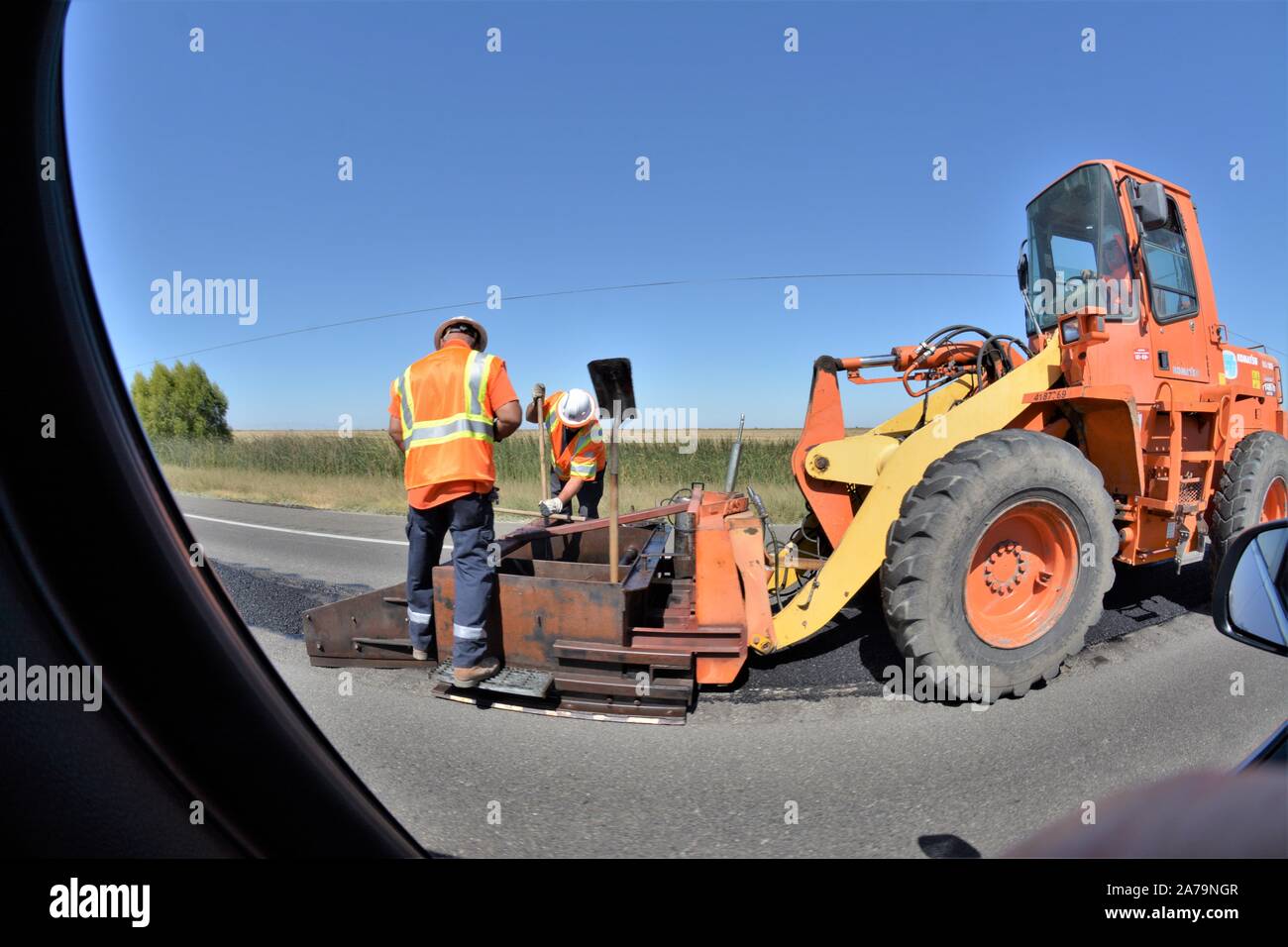 Road repair using front loader with paving machine attached by the