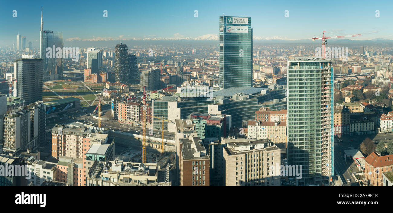 Milan Italy: Skyscraper, the Lombardy Region headquarters building with the Italian Alps and Monte Rosa in the background. City covered by smog Stock Photo