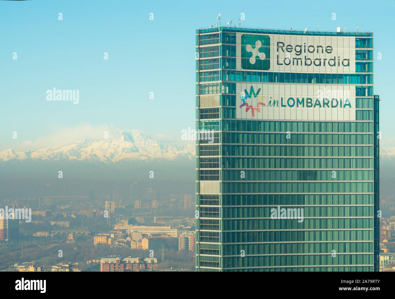 Milan Italy: The Lombardy Region headquarters building with the Italian Alps and Monte Rosa in the background. City of Milan covered by smog. Stock Photo