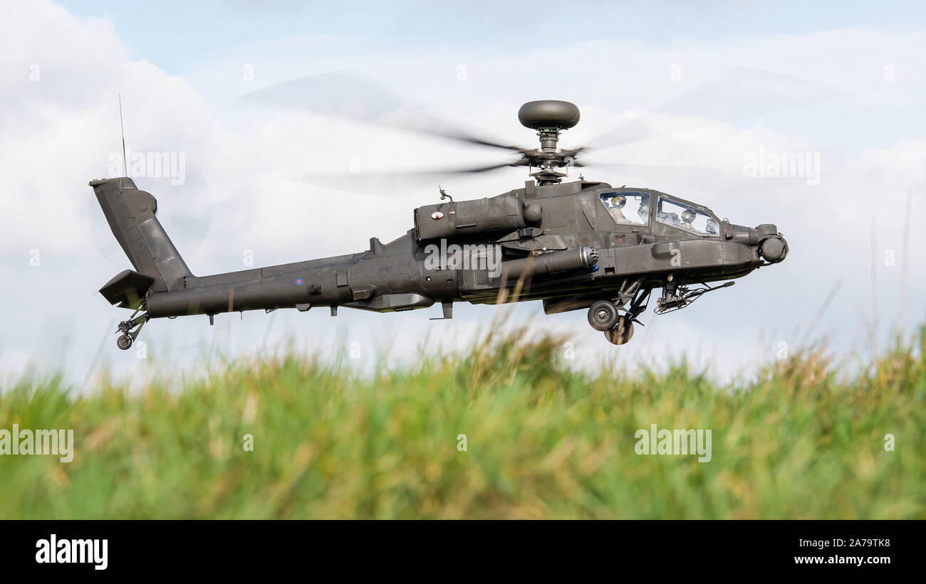 A British Army Apache attack helicopter of the Army Air Corps prowling around Salisbury Plain Training Area at low level during a training exercise. Stock Photo