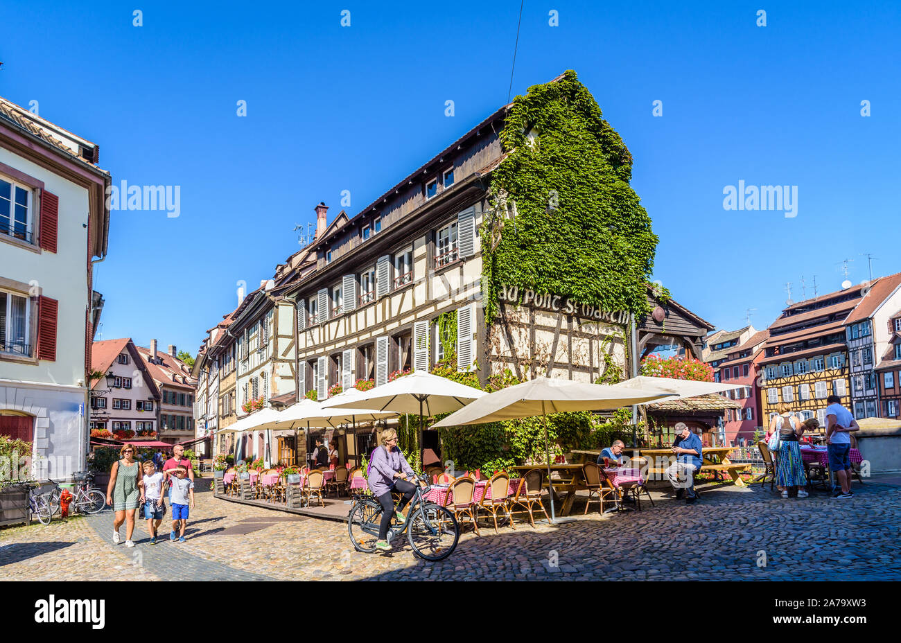Tourists strolling in front of the restaurant 'Au Pont Saint-Martin' set in a half-timbered house in the Petite France quarter in Strasbourg, France. Stock Photo