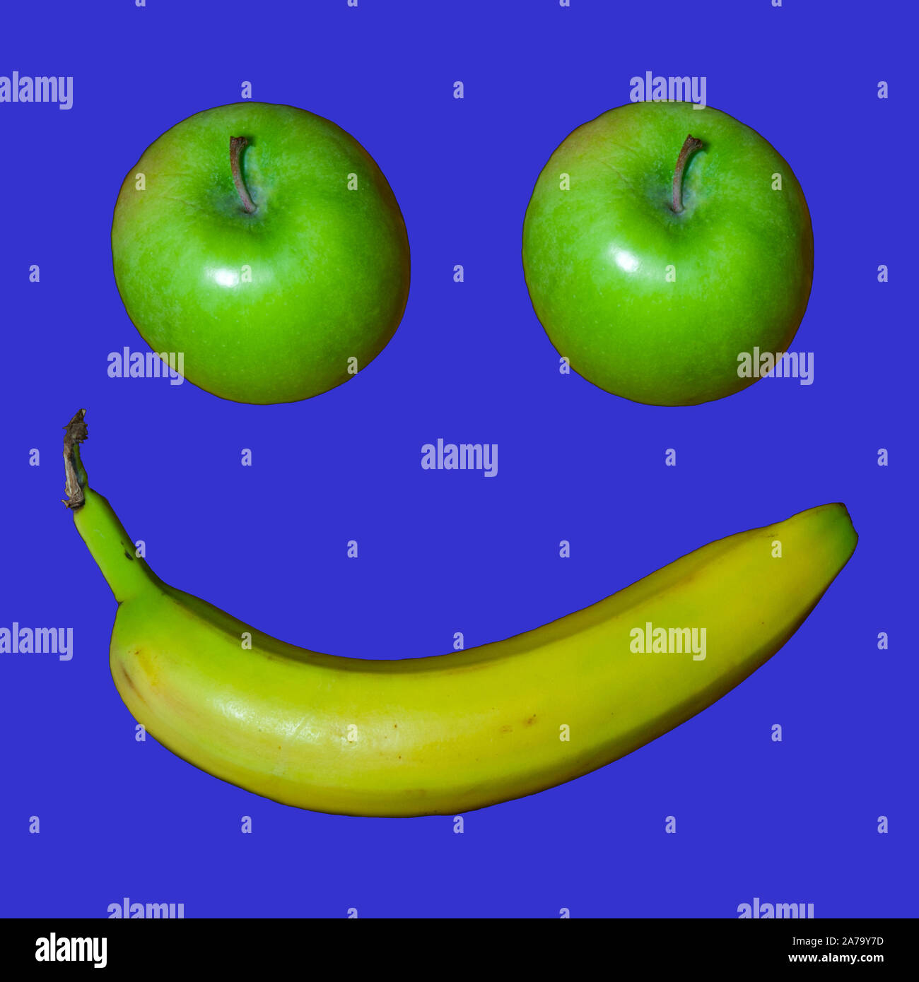 Two Granny Smith apples and a banana make a smiley face on a black background. Stock Photo