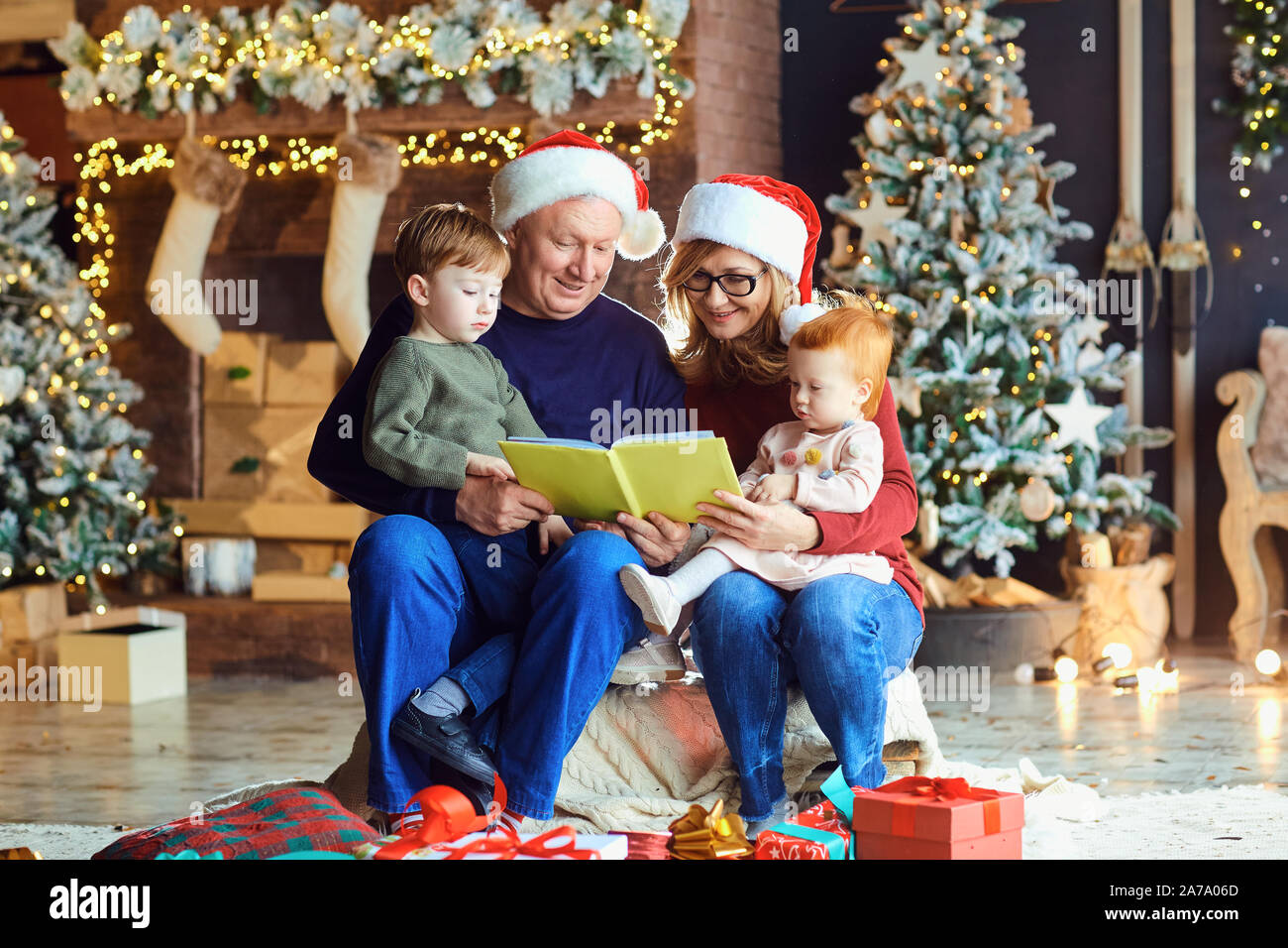 Grandparents read a book to children in Christmas Stock Photo