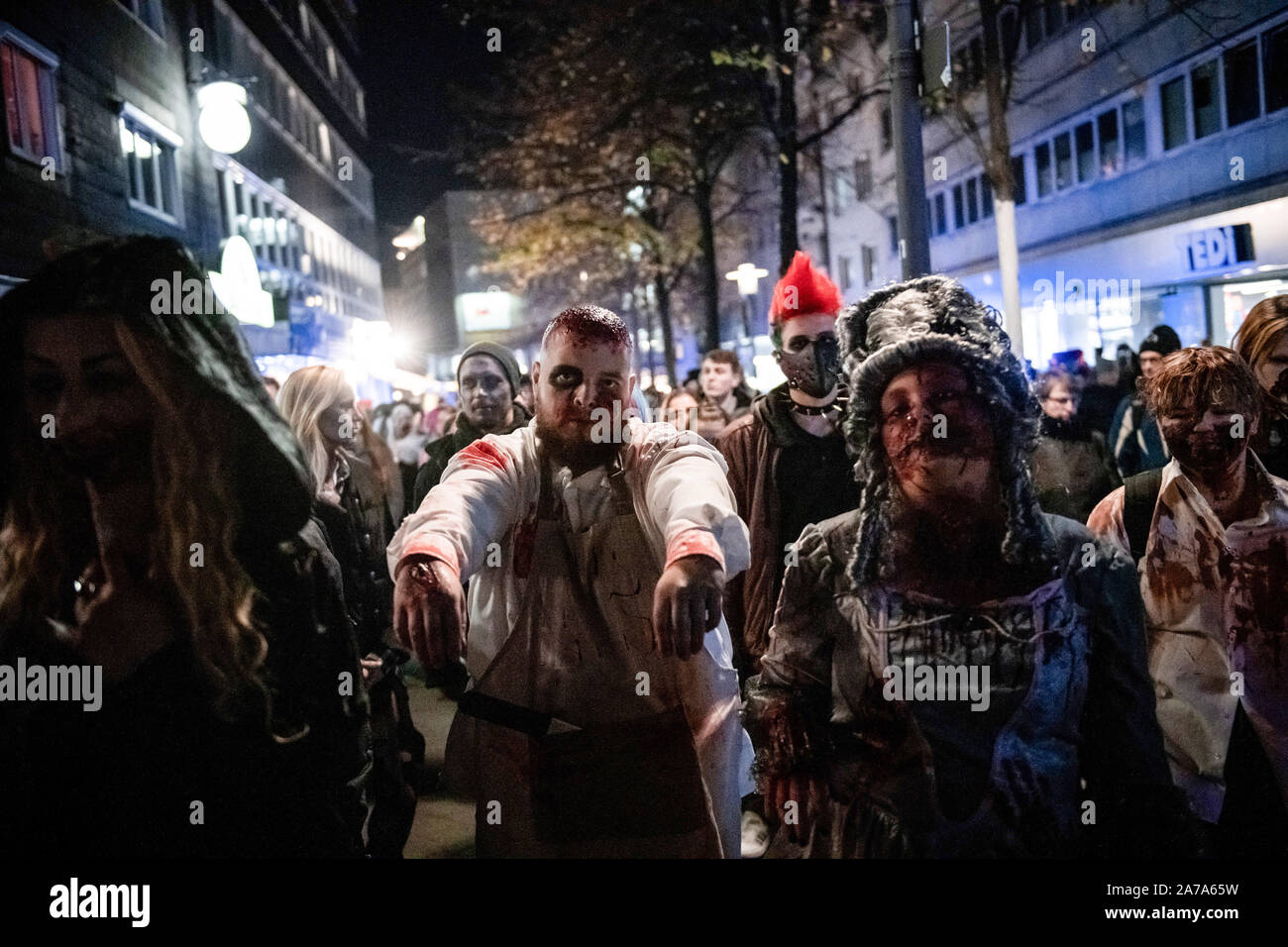 31 October 2019, North Rhine-Westphalia, Essen: Numerous people dressed as zombies roam the city centre of Essen. The 'Zombie Walk', which had been taking place on Halloween evening for several years, had been the subject of a fierce dispute, because the city's marketing company fears that visitors to a simultaneous light festival in the city might be disturbed. Instead of the zombie walk there is now a demonstration announced by the left and the green for more participation of the residents in the urban design. Photo: Fabian Strauch/dpa Stock Photo