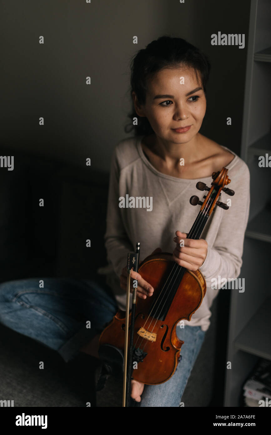 Beautiful young woman musician posing with a violin at home Stock Photo ...