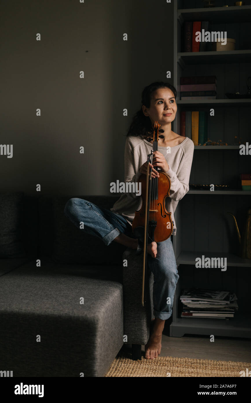 Beautiful young woman posing with a violin at home Stock Photo - Alamy