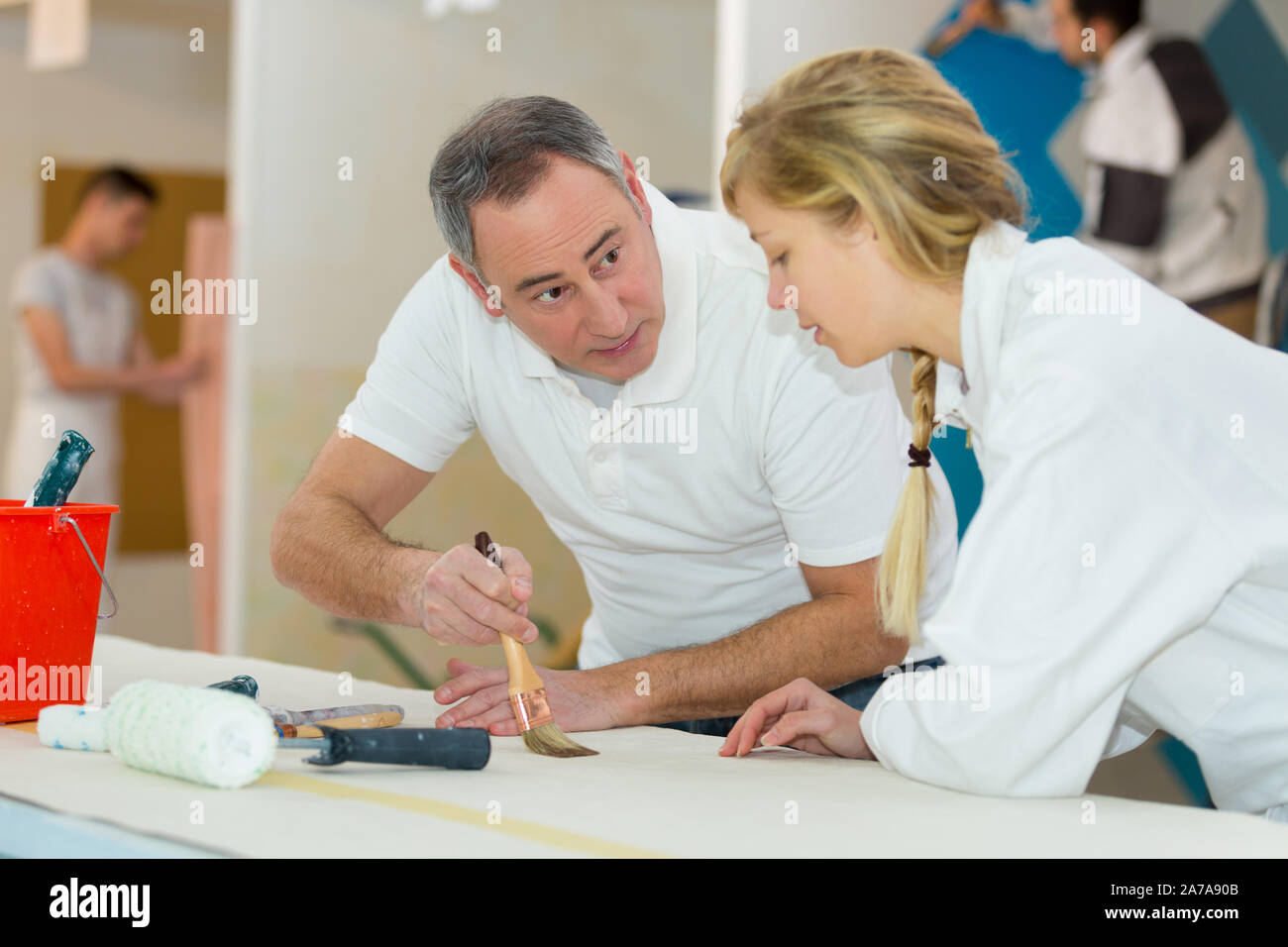 painter teaching paintbrush technique to apprentice Stock Photo