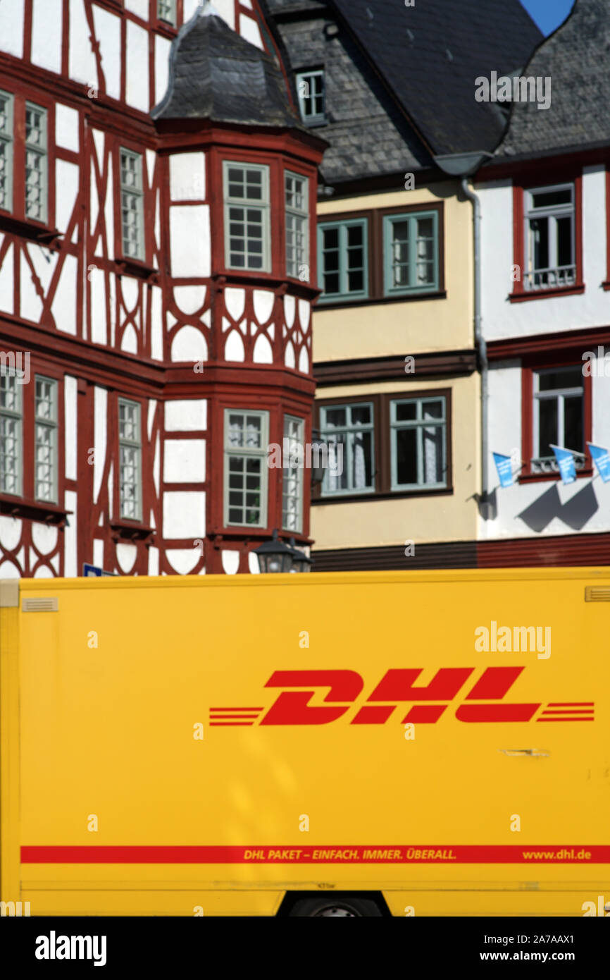Limburg, Germany - October 12, 2019: A parcel of DHL parcel service stands in front of half-timbered houses of the listed Old Town on October 12, 2019 Stock Photo