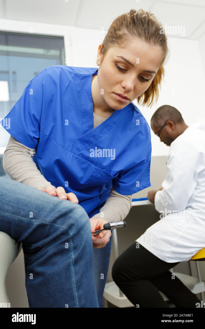 female neurologist testing knee reflex with a hammer Stock Photo Alamy