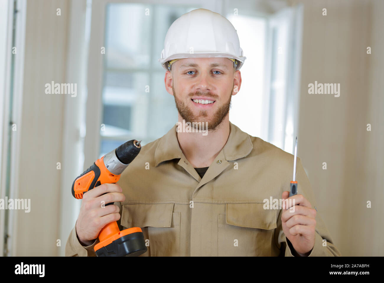 portrait of happy builder handyman with electric drill indoors Stock Photo