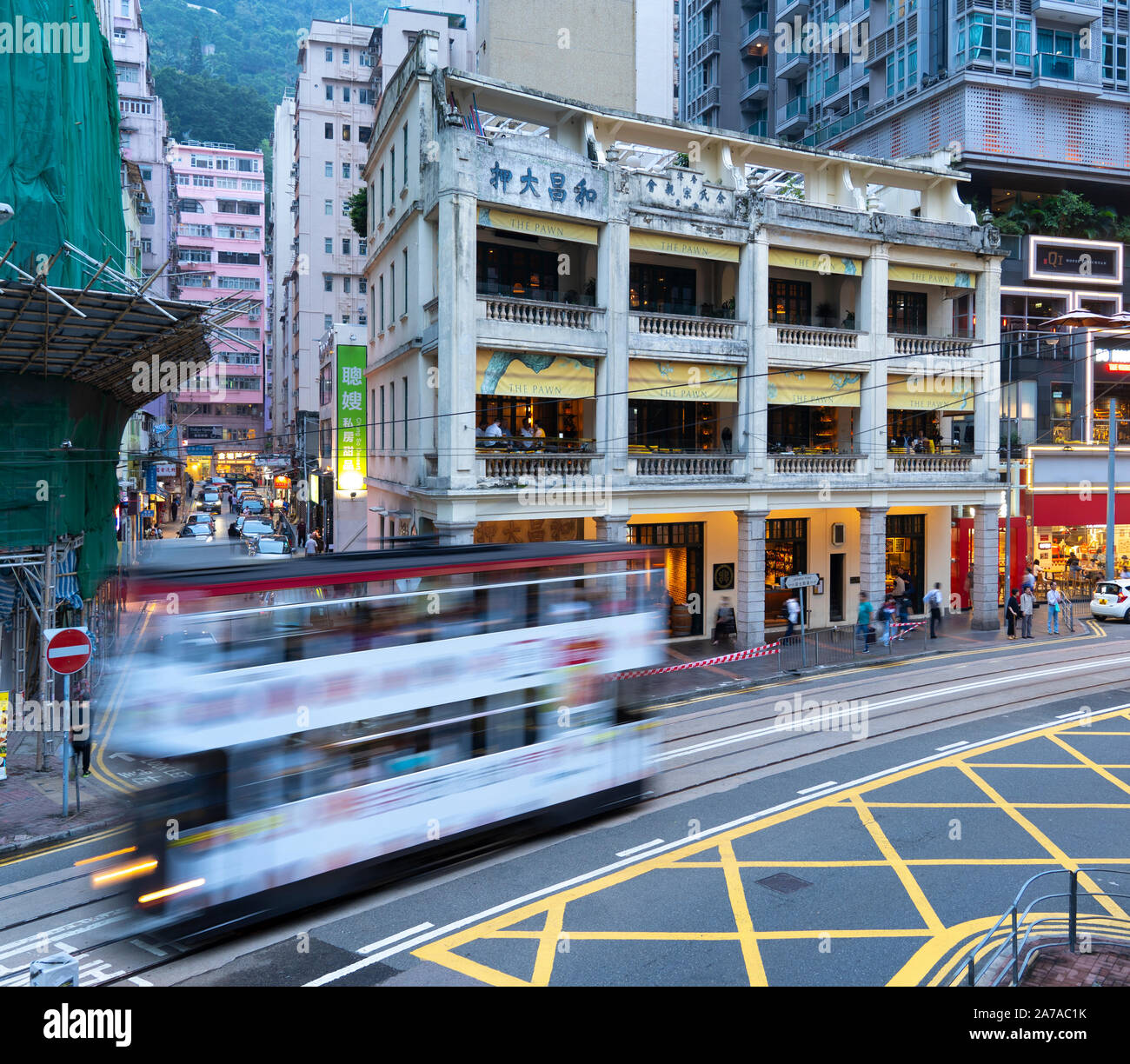 Tram passing old colonial building now restaurants and bar called The Pawn in Wanchai, Hong Kong Stock Photo