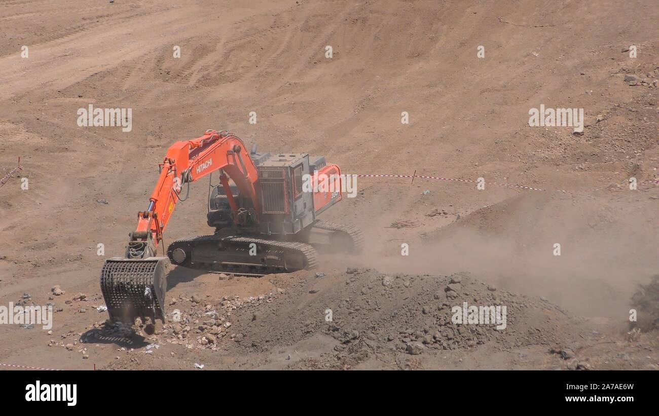 Enginers of 4M defense use an armored excavator with tillers and special screening buckets to clear mines from old Syrian minefield on Gofra beach in the sea of Galilee, Israel Stock Photo