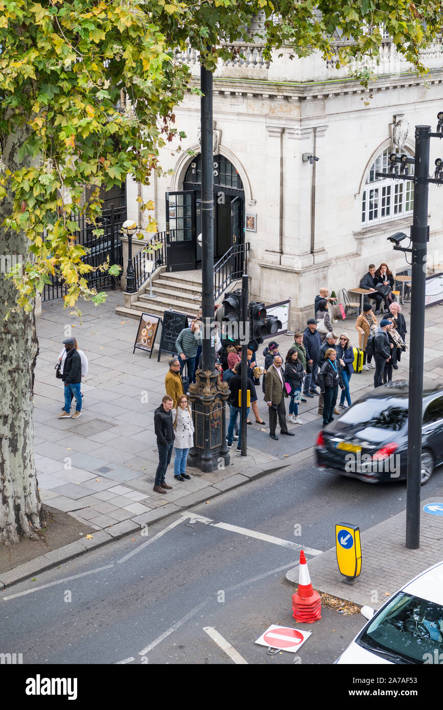 People wait at a pedestrian crossing to cross the road on Victoria