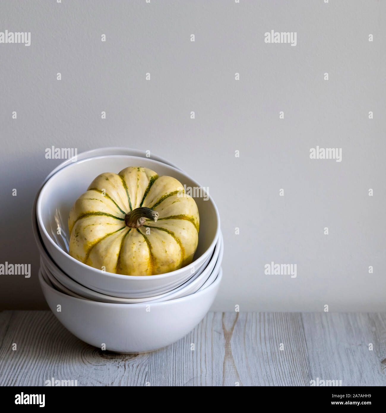 pumpkins in a bowl on a white table as a decoration of the kitchen interior Stock Photo