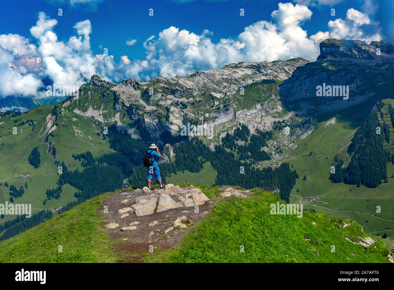 Photographer traveler takes a photo of the alpine valley on a Mannlichen mountain viewpoint, Bernese Oberland Switzerland Stock Photo