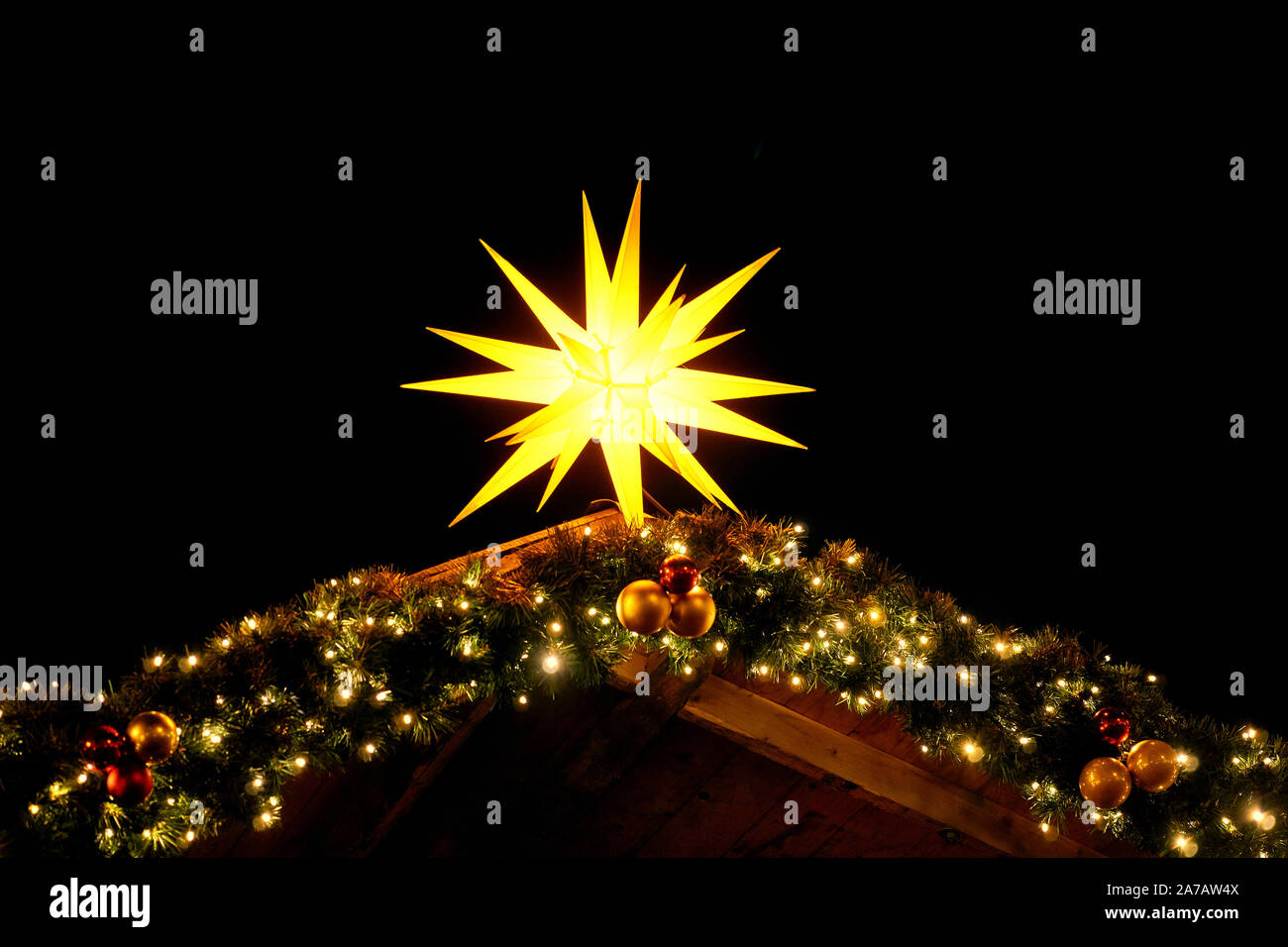 Luminous christmas star on fir branches with christmas tree balls. Christmas decoration in the night. Stock Photo