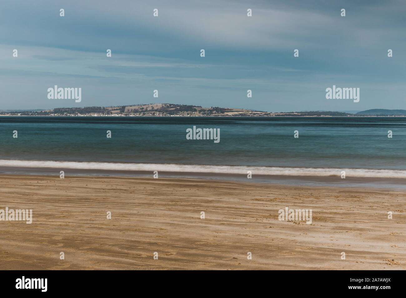 long exposure shot of pristine deserted Australian beach at dusk in Tasmania with moody tones and silky water effect and detail of coastline Stock Photo