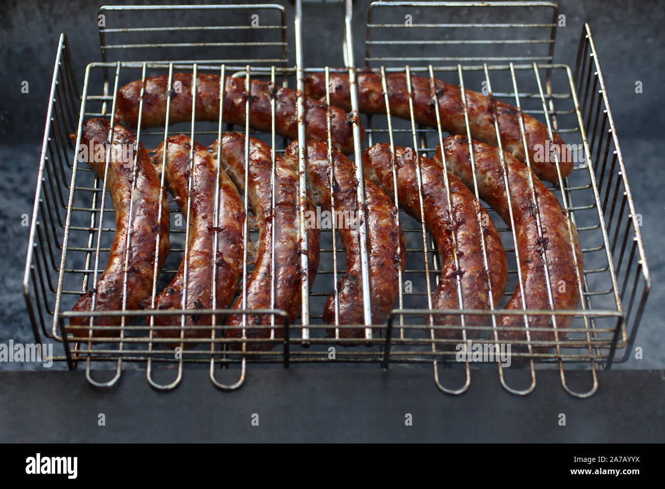 Meat sausages squeezed between grill grates, frying on a grill brazier  Stock Photo - Alamy