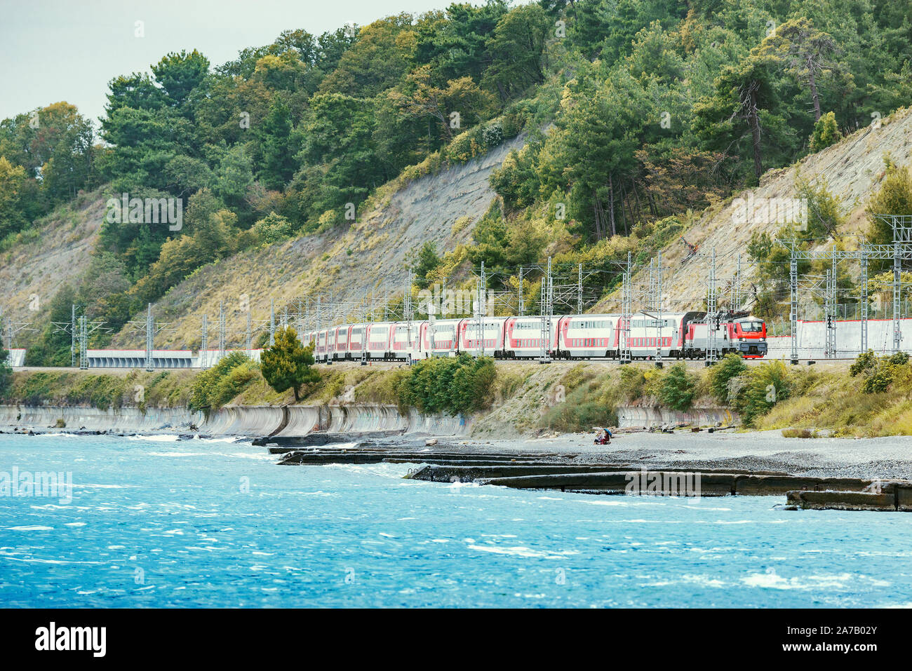 Passenger double deck train moves along the Black sea beach. Sochi. Stock Photo