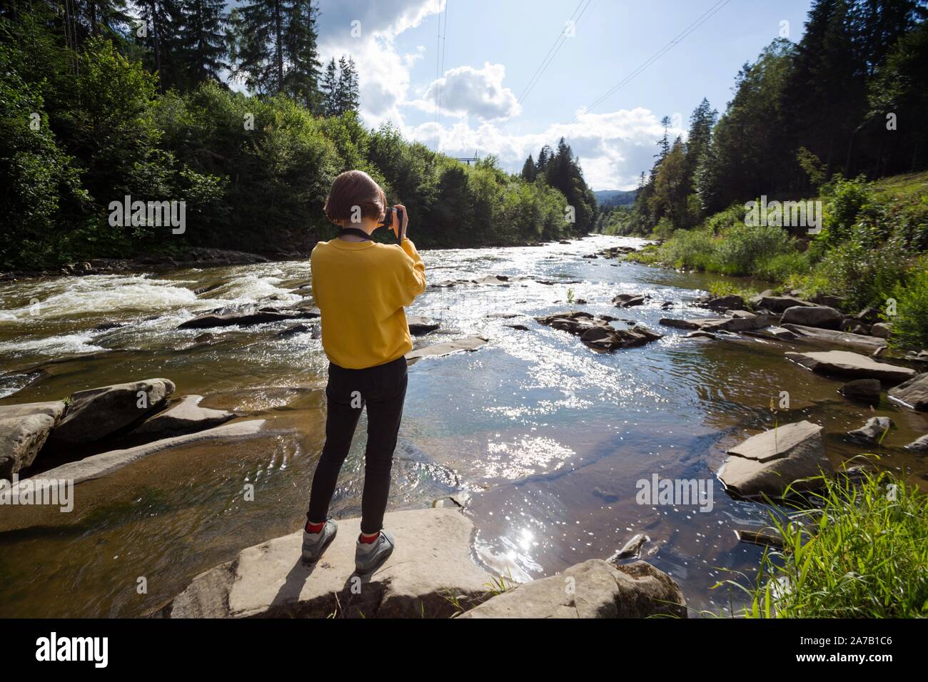 tourist girl with camera standing on the bank of a mountain river Stock ...