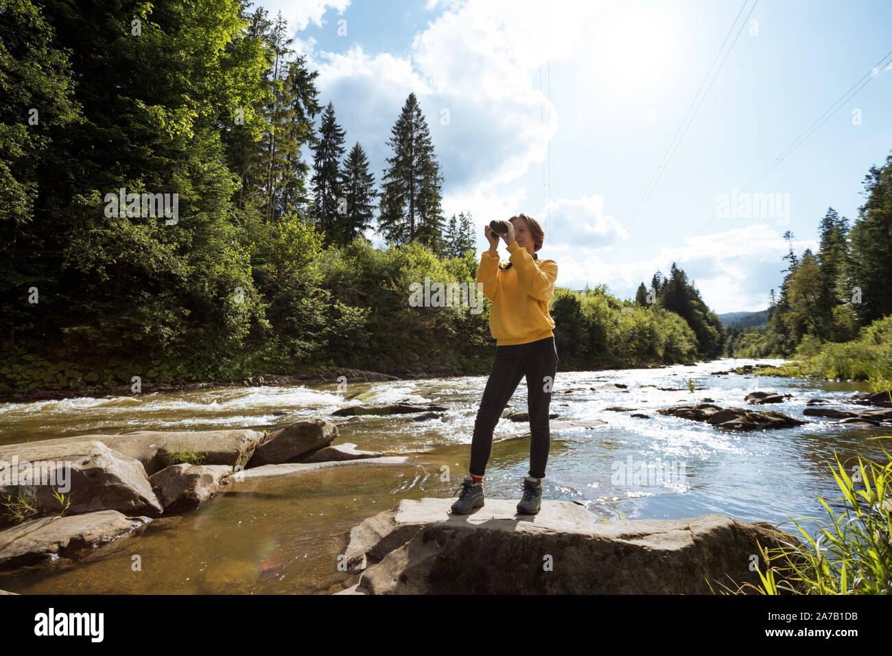 tourist girl with camera standing on the bank of a mountain river Stock ...