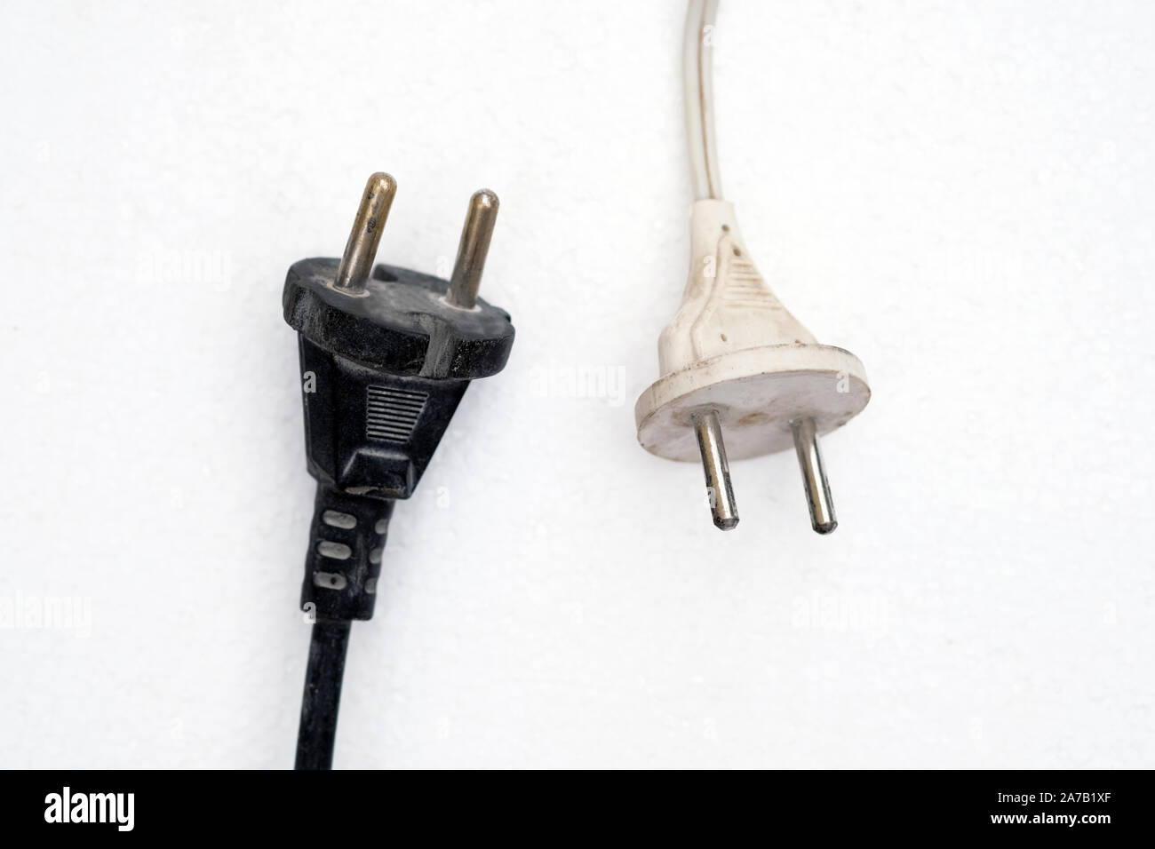 Two electric plugs close up. White and black electric plugs with wires on a white background. Old electric plugs with cords. Stock Photo