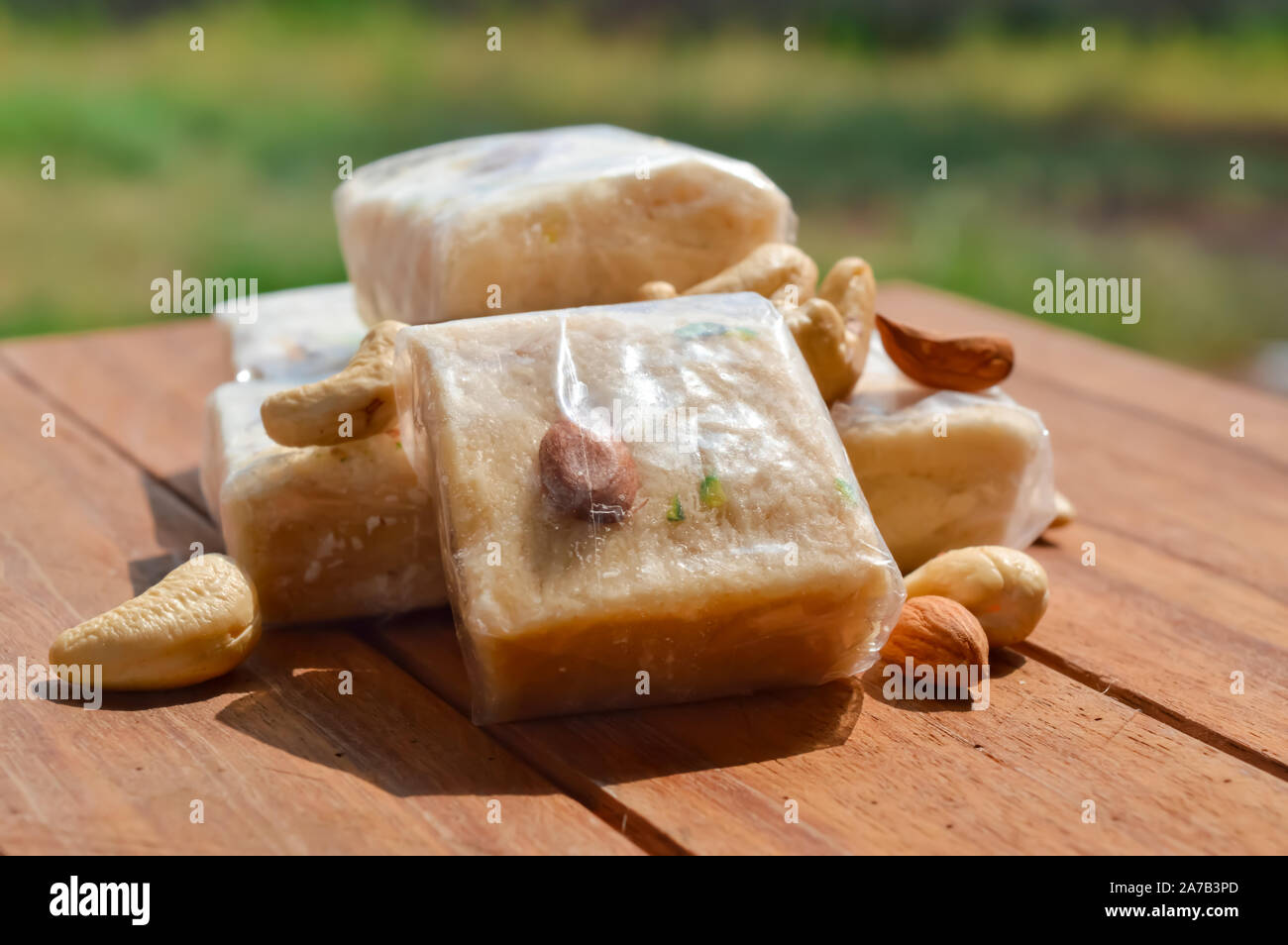 Patisa / Soan Papdi is a popular Indian cube shape flakey/crispy dessert.sonpapdi and nuts on wooden table Stock Photo