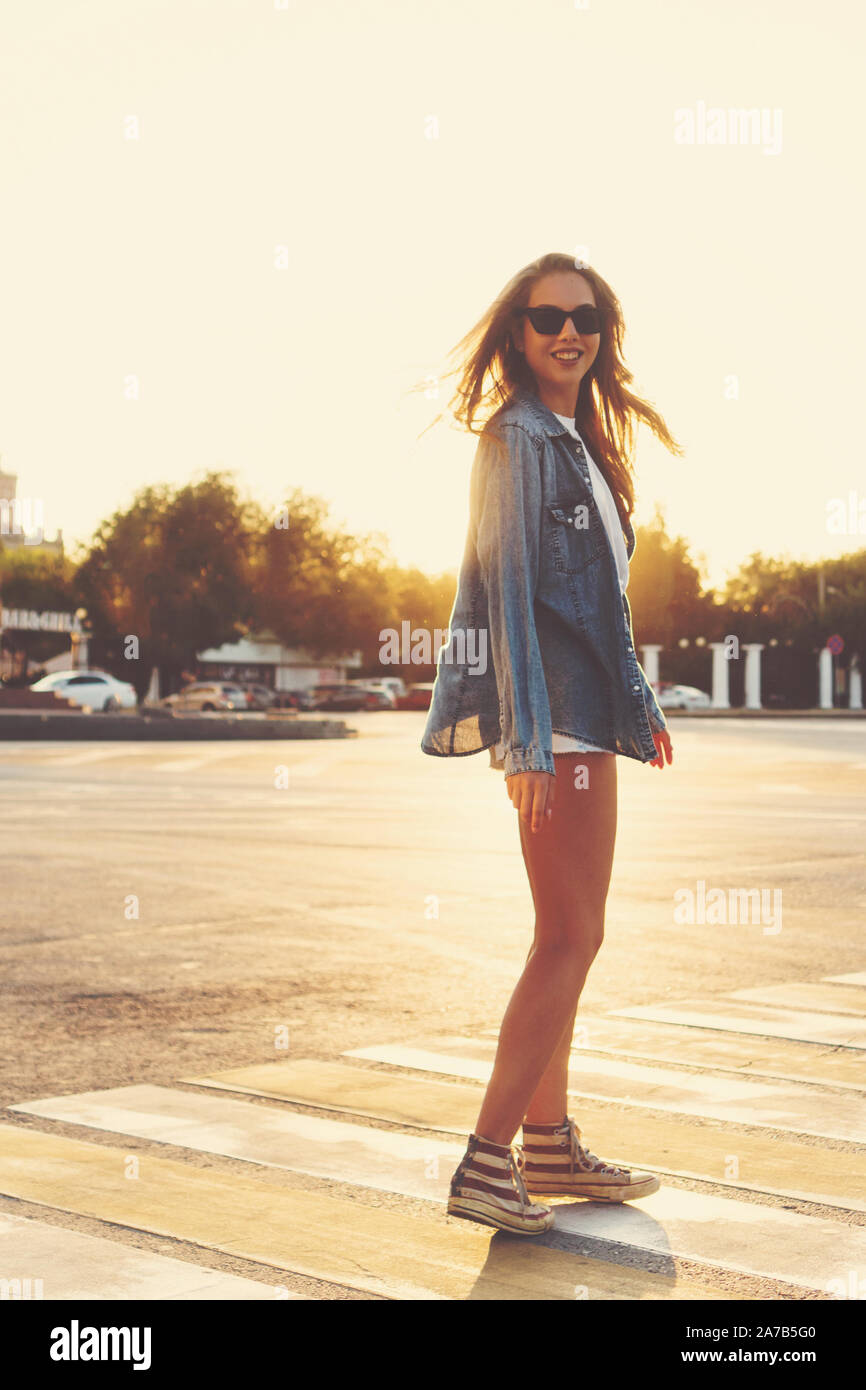 Lovely teenager girl posing at the crosswalk in the sunset. Happy summer, vacation, travel. Summertime. Lifestyle. People, street style and holidays c Stock Photo