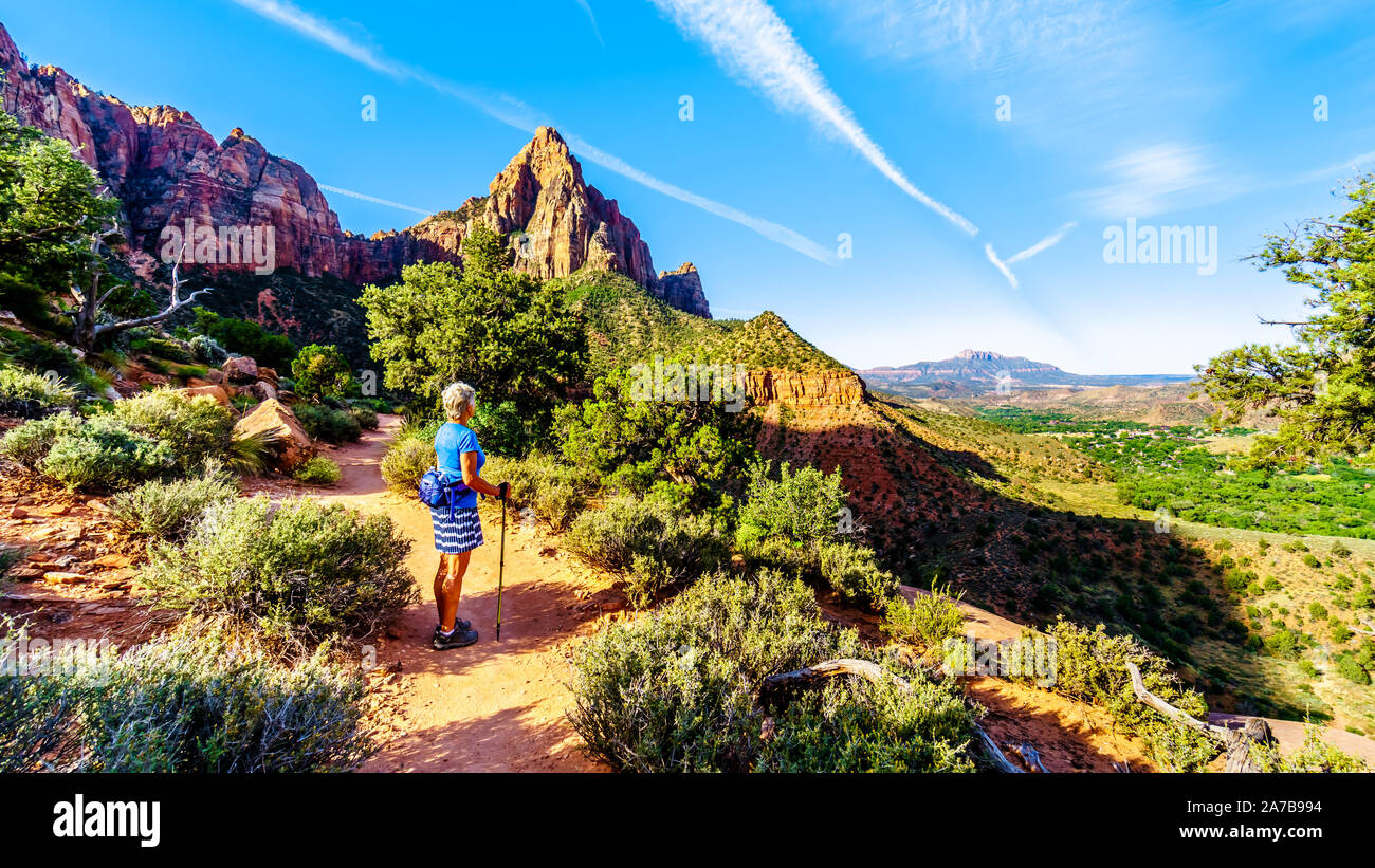 Woman hiker watching the sunrise over The Watchman peak in Zion National Park in Utah, USA, during an early morning hike on the Watchman Trail. Stock Photo