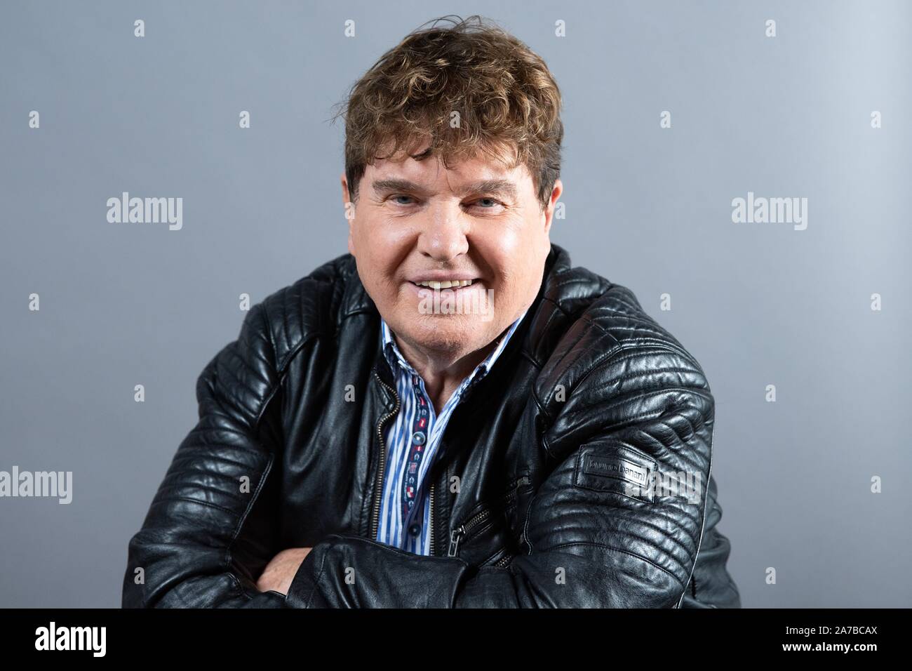 Dresden, Germany. 30th Oct, 2019. The singer Frank Schöbel sits in front of a photo wall in the boulevard theatre. The occasion is the presentation of the musical "Frank Schöbel Story", which deals with the career of the GDR hit singer Frank Schöbel on stage. Credit: Sebastian Kahnert/dpa-Zentralbild/dpa/Alamy Live News Stock Photo