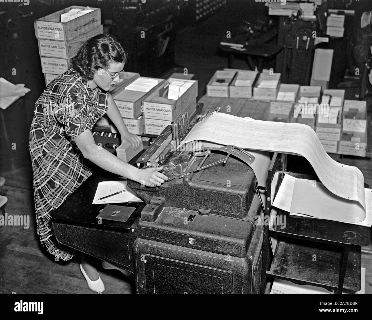 A Records Office worker at a machine which is listing in numerical