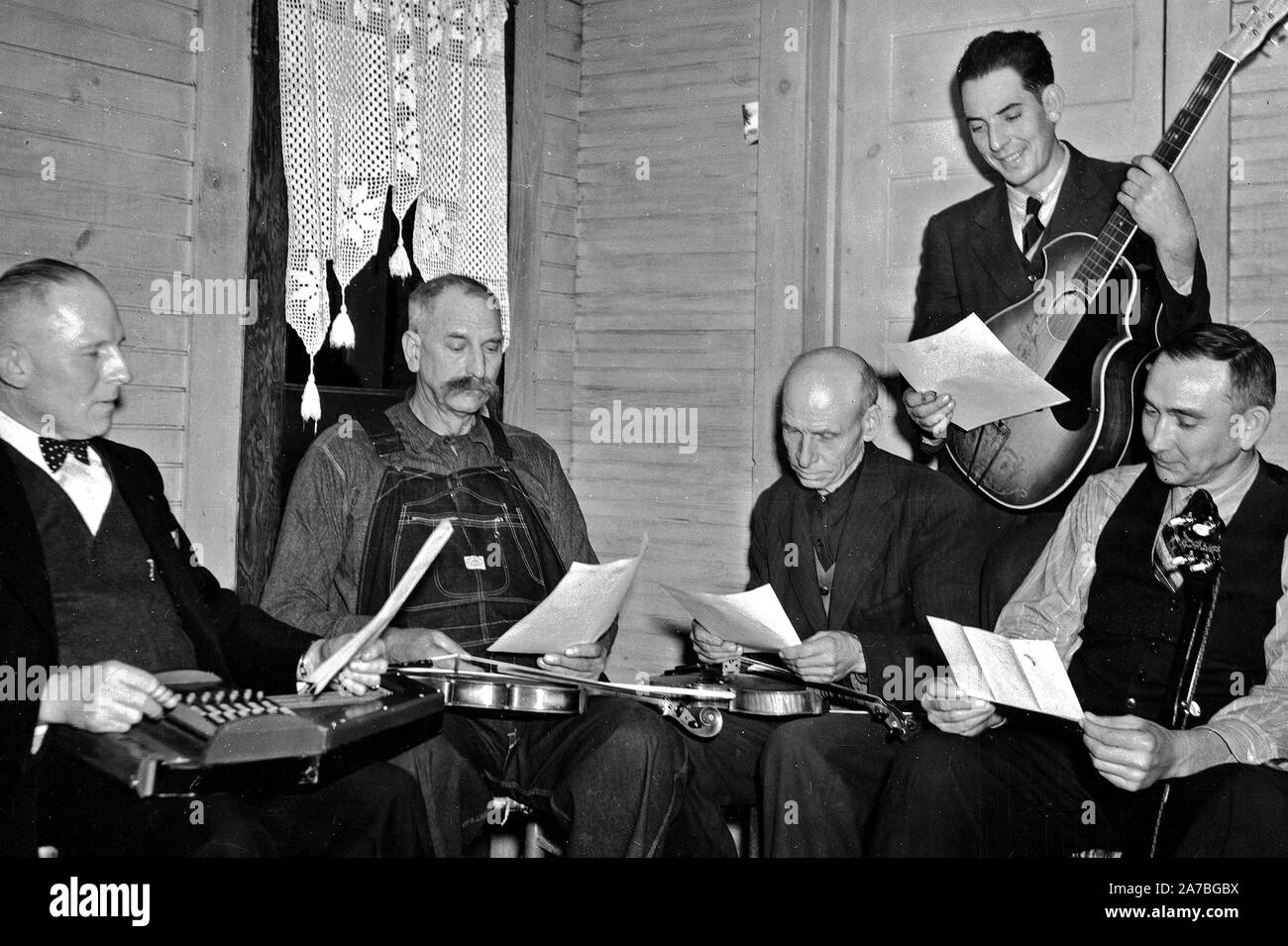 Bog Trotters Band members seated with instruments, Galax, Va. Includes Doc Davis, with autoharp; Crockett Ward, with fiddle; Uncle Alex Dunford, with fiddle; Wade Ward, with banjo; Fields Ward, with guitar ca. 1937 Stock Photo