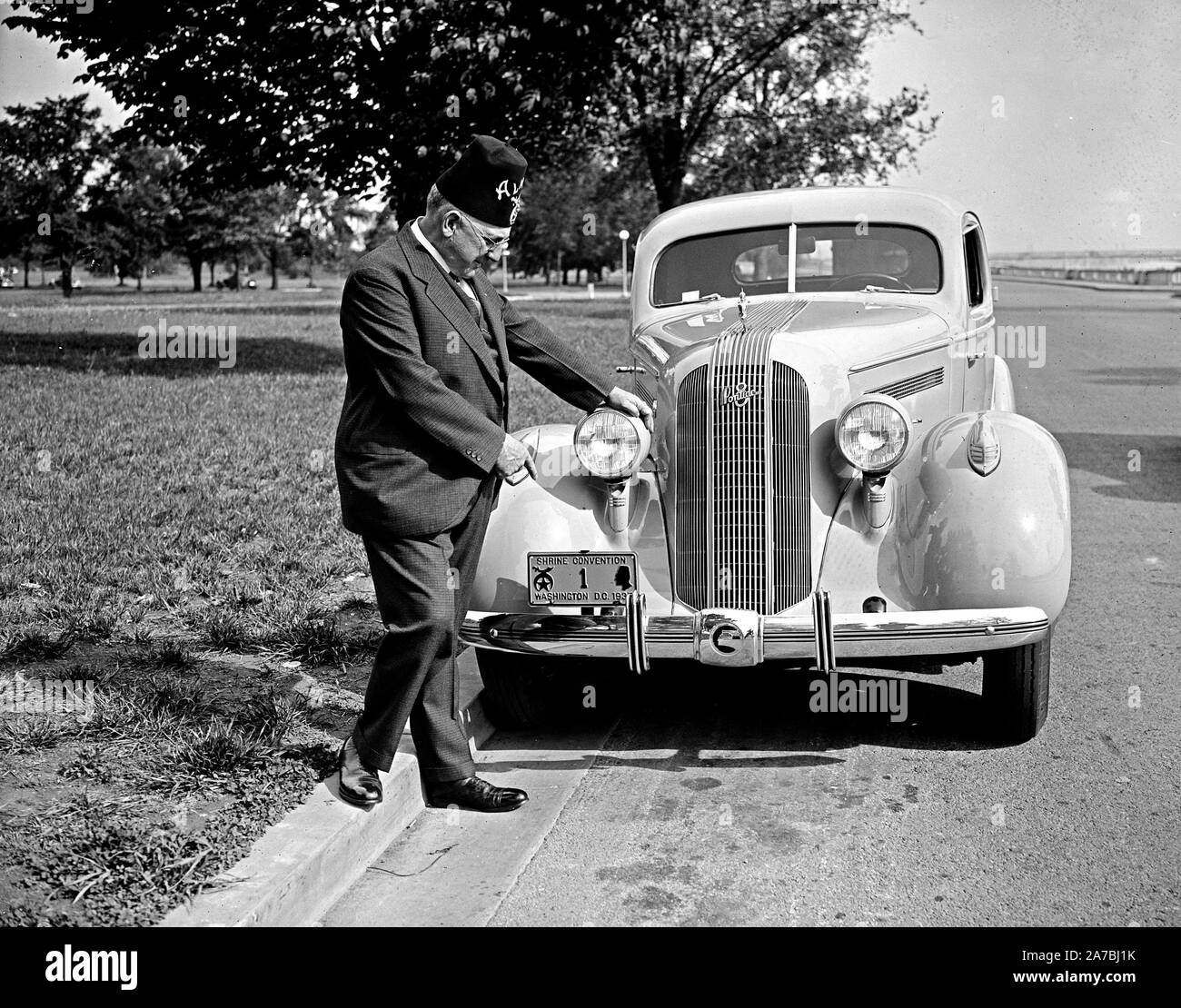 Shriner L.P. Steuart standing by car, pointing at personalized license plate ca. 1935 Stock Photo