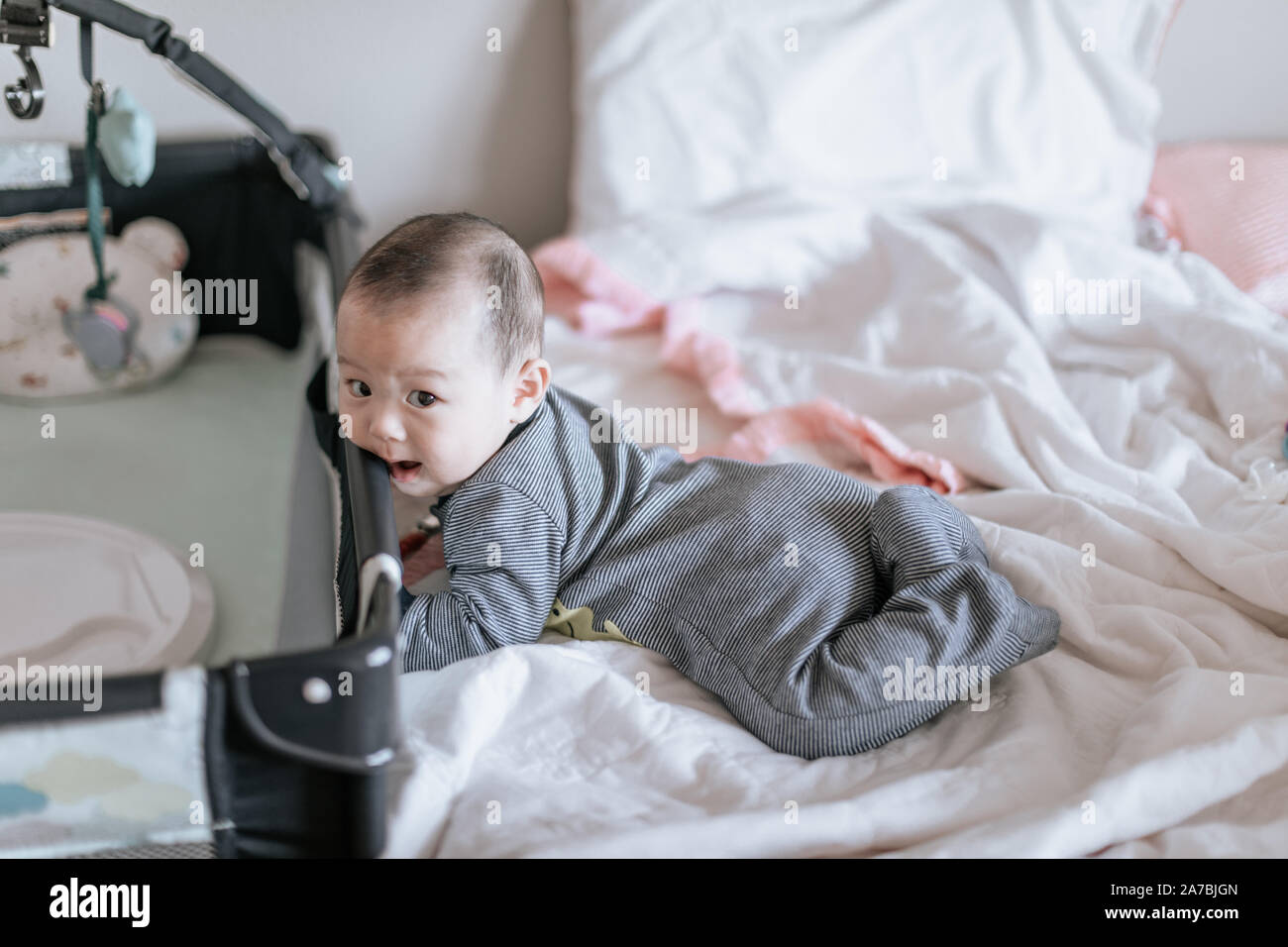 Cute asian baby trying to get out of bed in the morning at home Stock