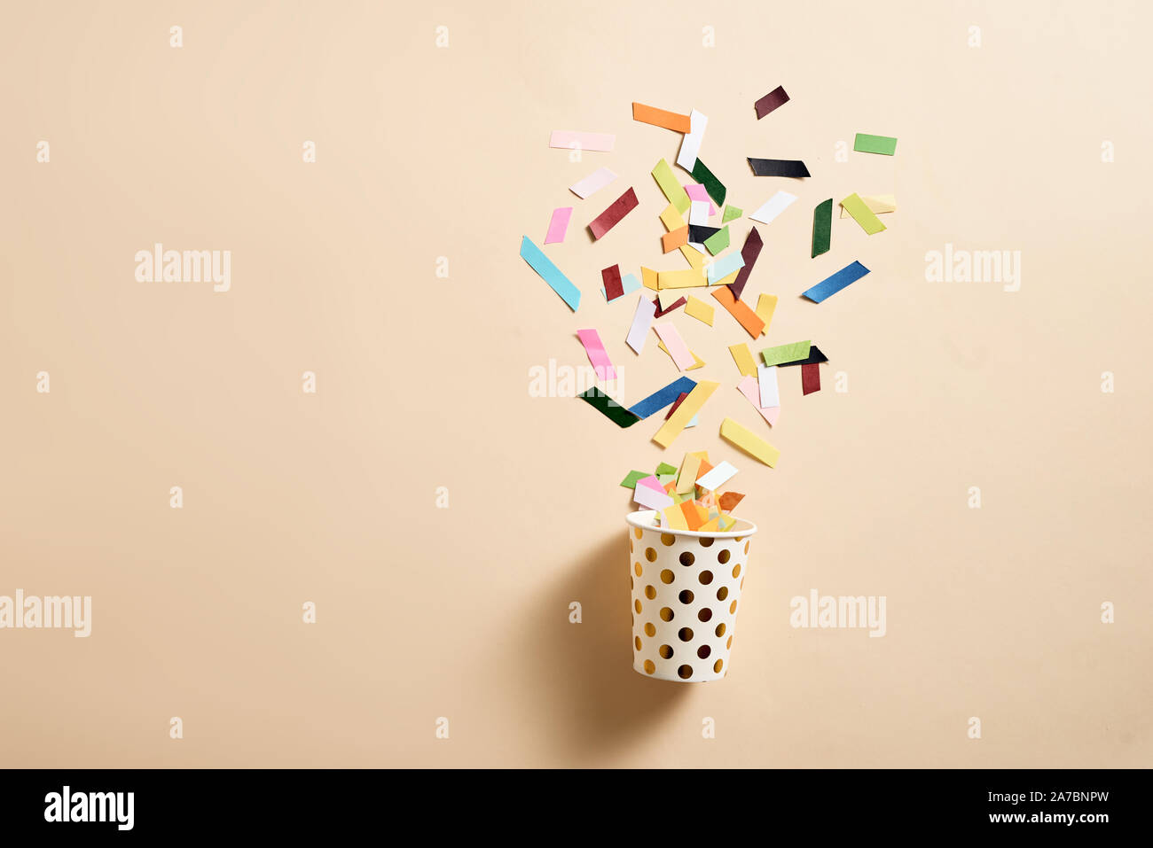 Drinking paper cup with multicolored confetti scattered on party ...
