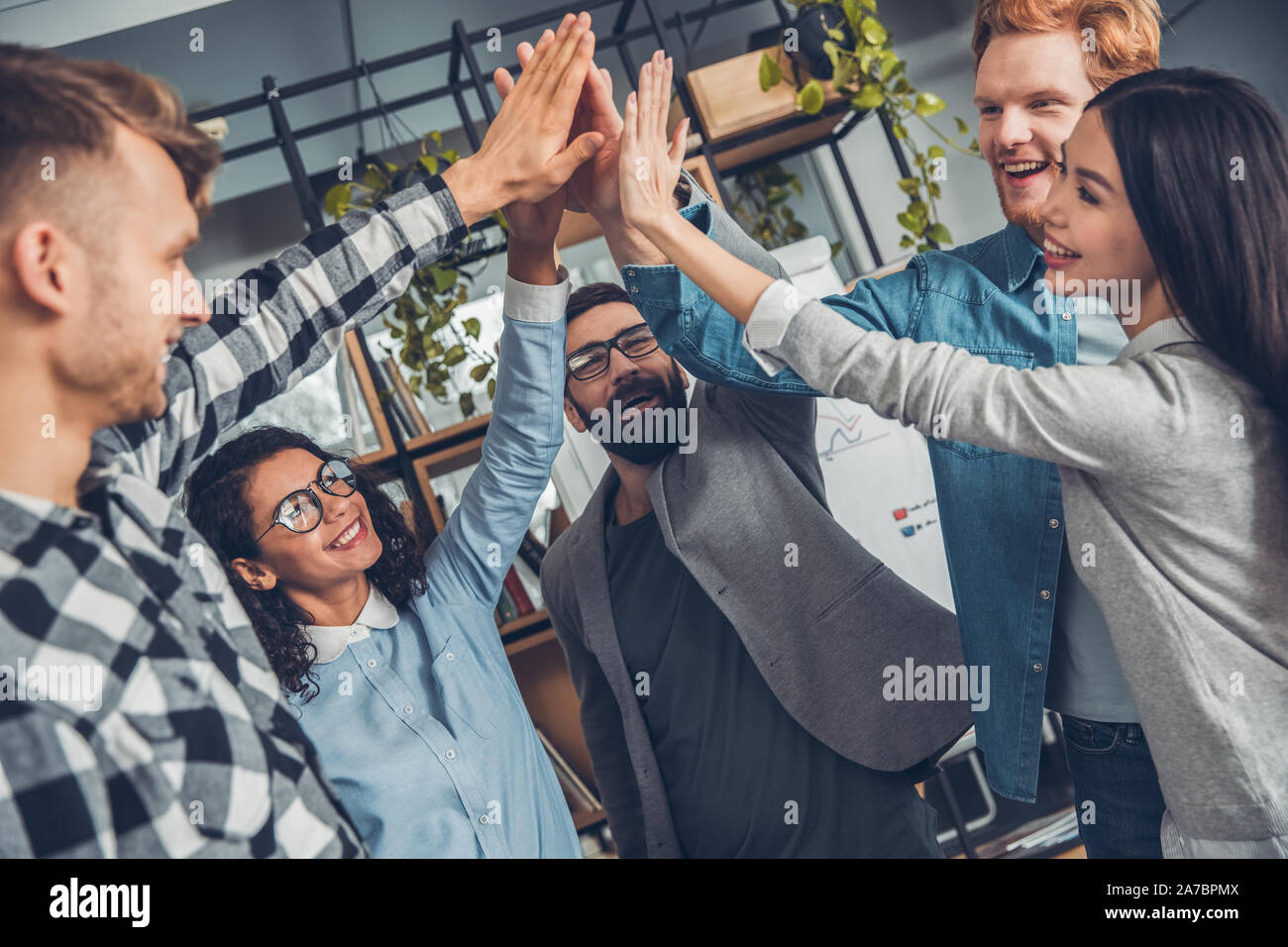 Young business people working at office standing giving high five ...