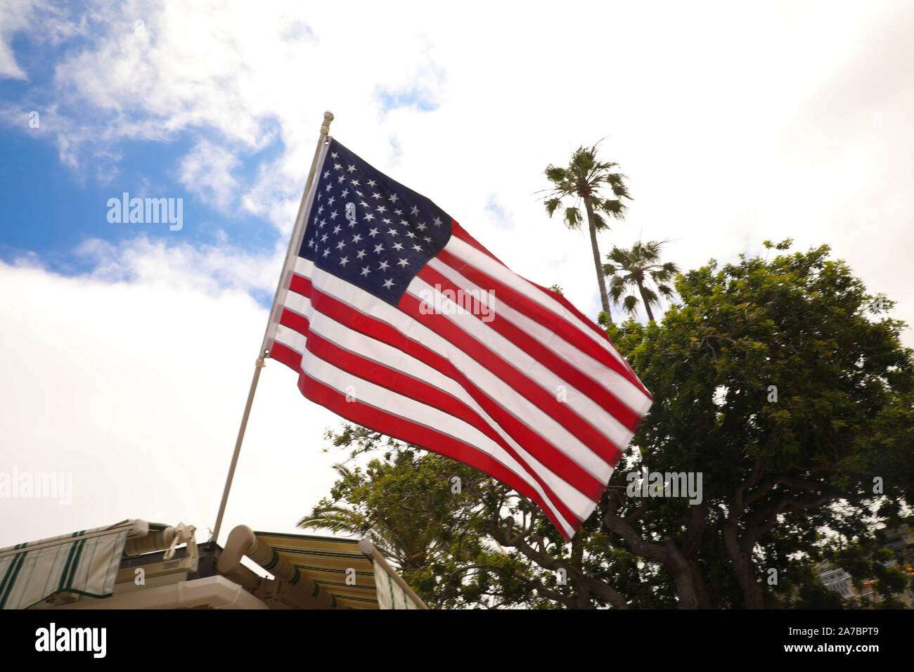 waving USA flag on pole against blue sky Stock Photo - Alamy