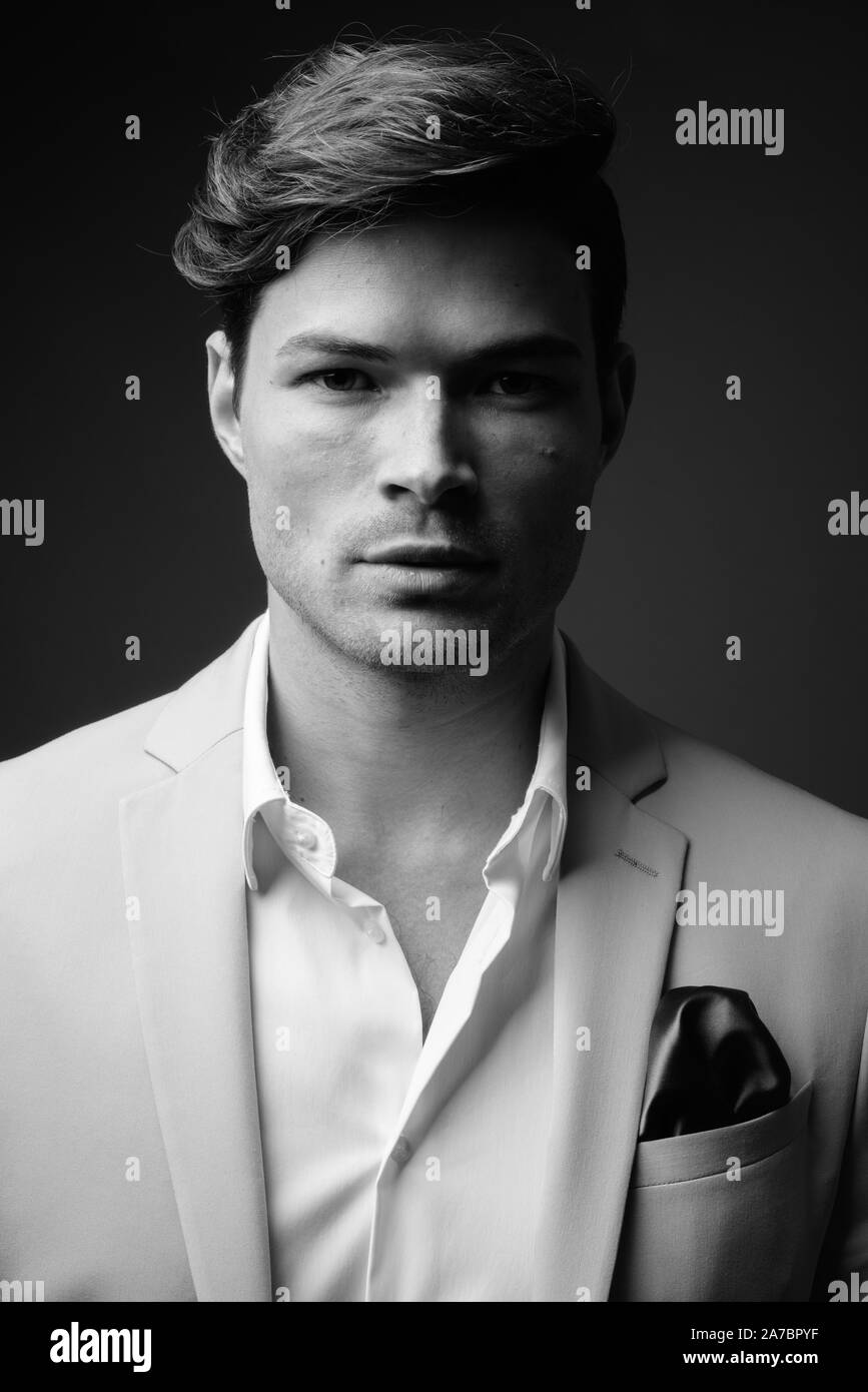 Portrait of young handsome businessman wearing suit in black and white ...