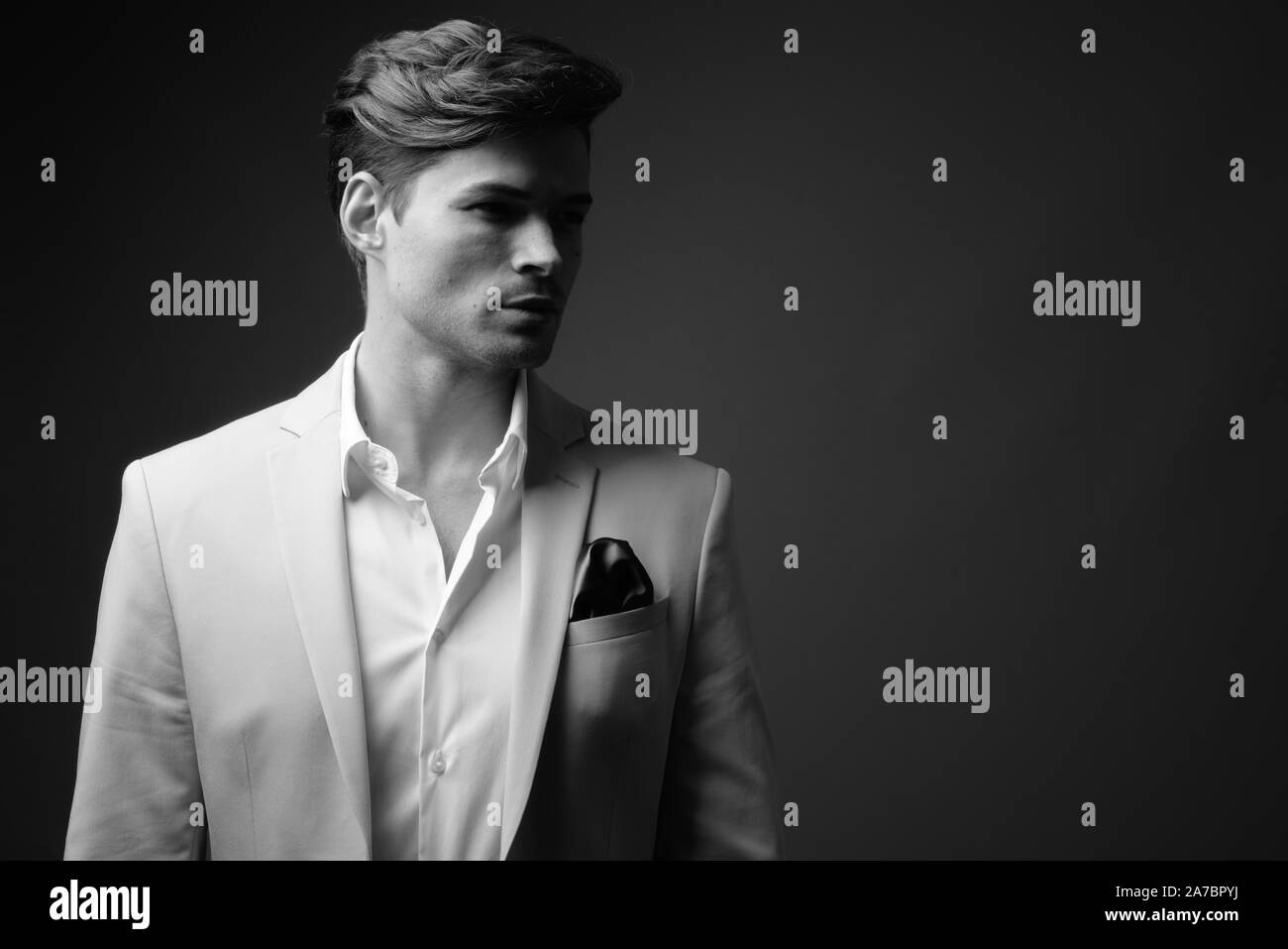 Portrait of young handsome businessman wearing suit in black and white ...