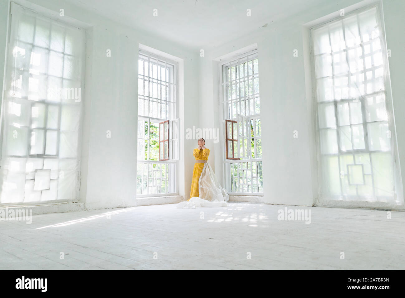 Loneliness Concept. A Woman In A Yellow Dress Is Standing In The Corner Stock Photo