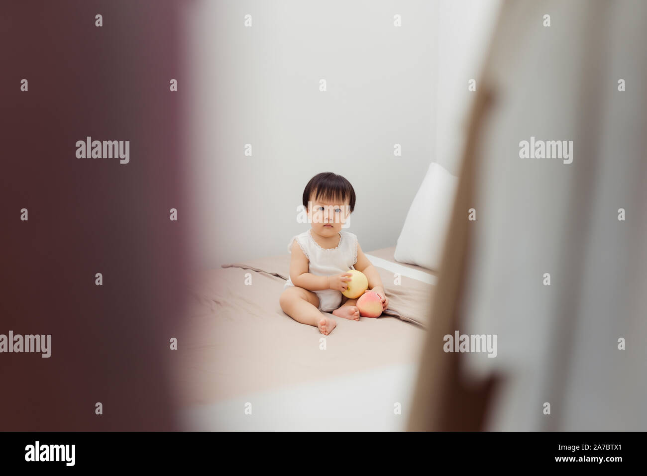 Funny happy toddler girl playing with toy on bed. Kids play at home. Stock Photo