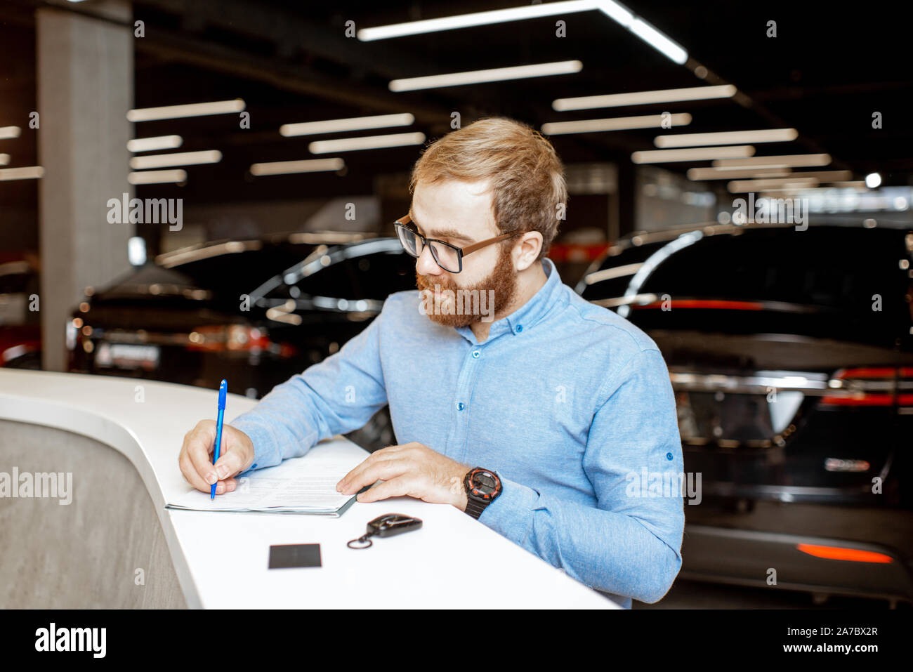 Young man signing some documents, buying or renting a car in the modern