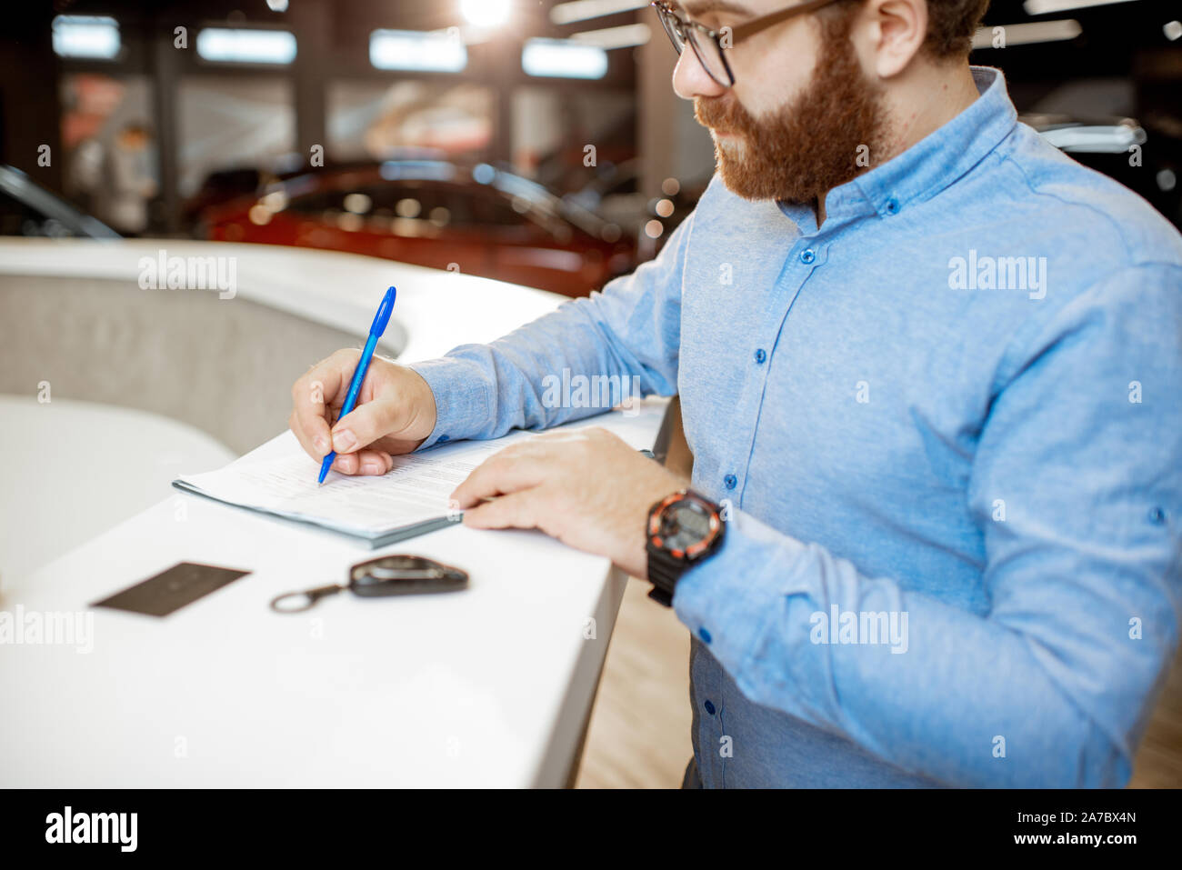 Young man signing some documents, buying or renting a car in the modern