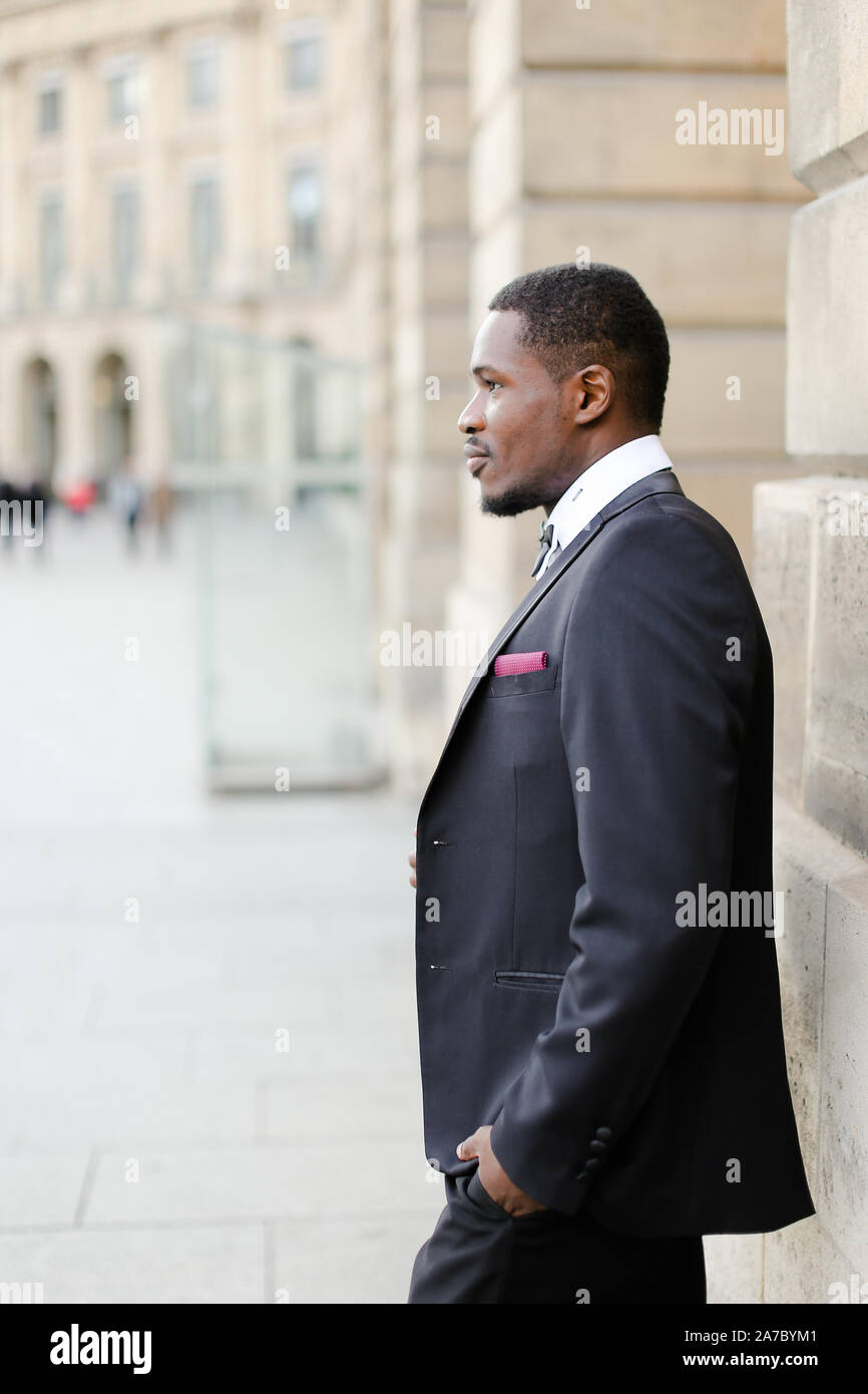 Afro american man wearing black suit and standing near building Stock ...