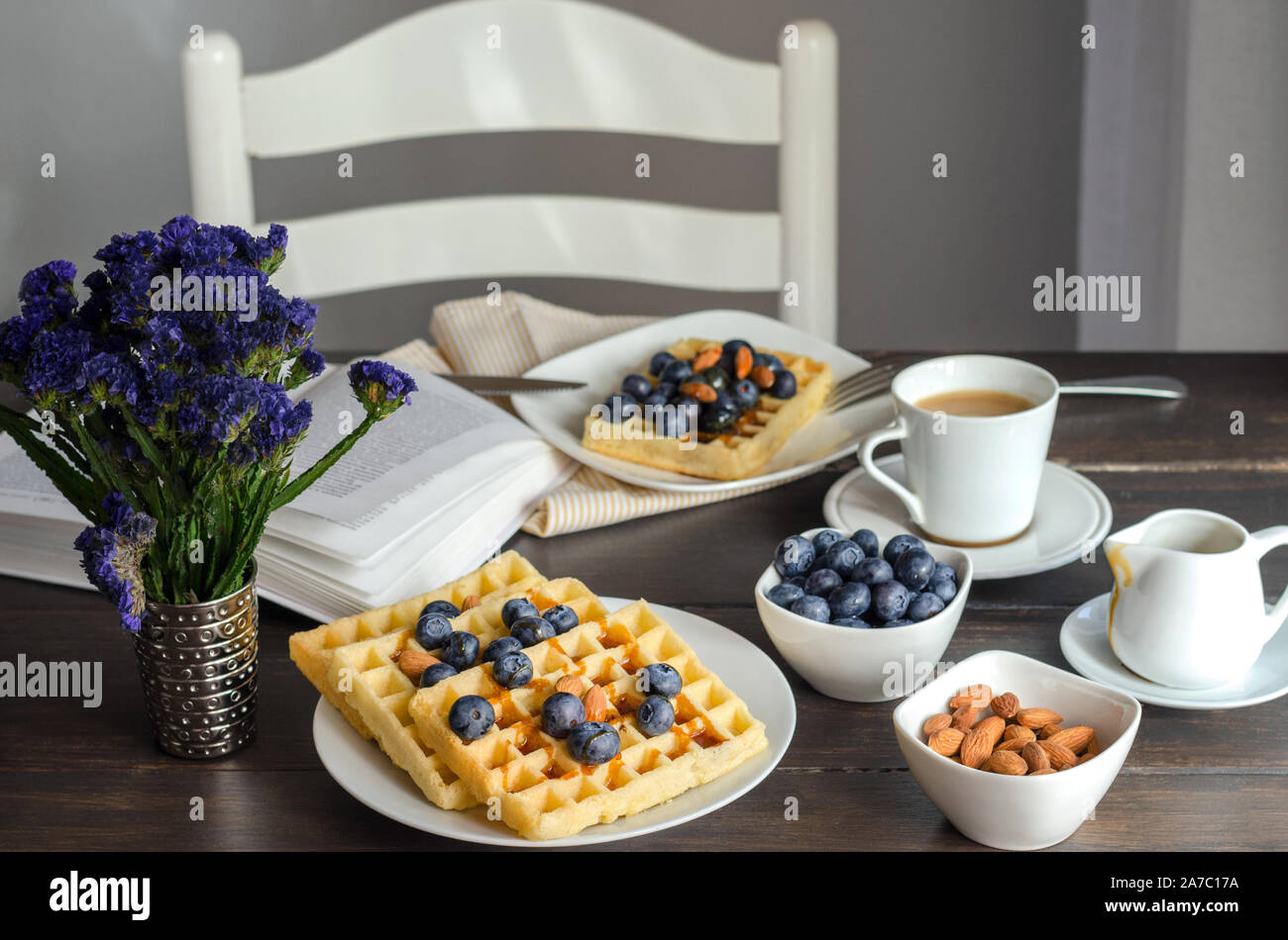 Belgian waffle decorated  with blueberries and nuts, open book on wooden table for perfect  breakfast at Sunday. Homemade dessert background. Relax mo Stock Photo