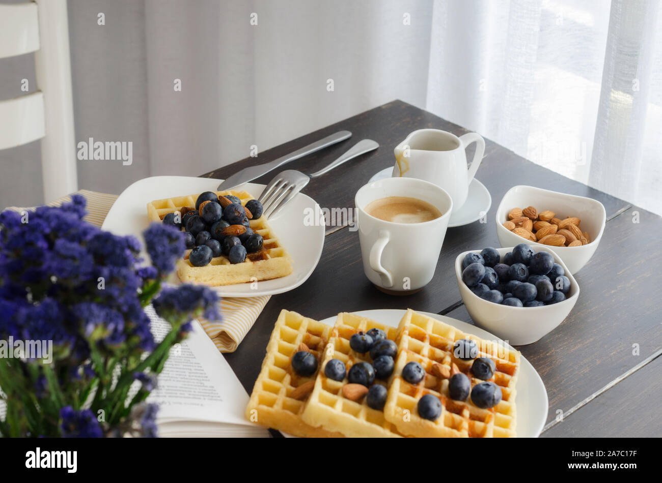 Belgian waffle decorated  with blueberries and nuts, open book on wooden table for perfect  breakfast at Sunday. Homemade dessert background. Relax mo Stock Photo